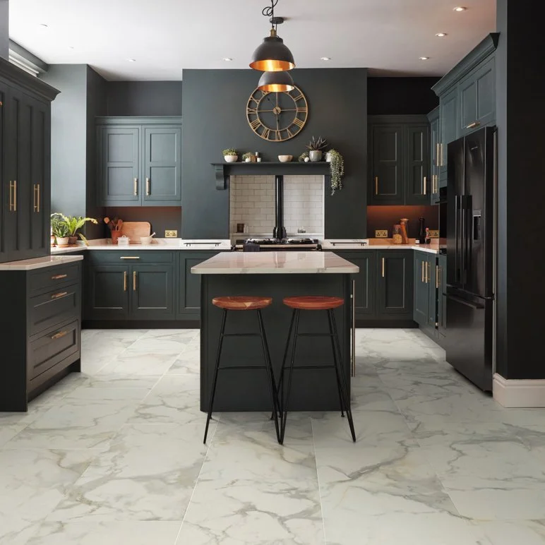 a white marble floor installed in a stylish kitchen with deep grey cabinets and wood barstools