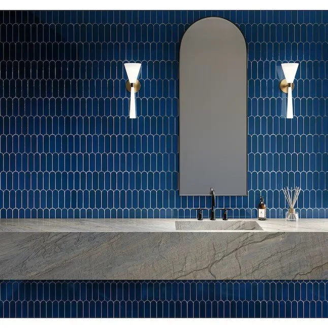 trendy, vibrant blue tiles with white grout installed behind a stone counter and stunning oval mirror