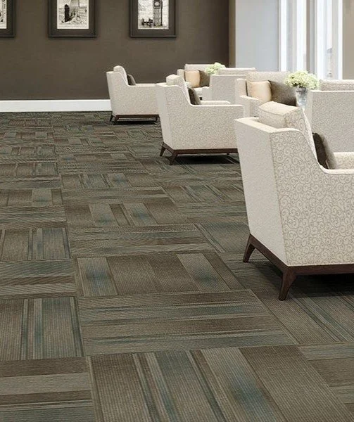 Carpet tiles in shades of beige, copper, and installed in a room with attractive cream armchairs