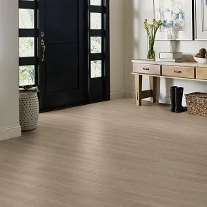 a light woodgrain floor installed in an entryway with a black door