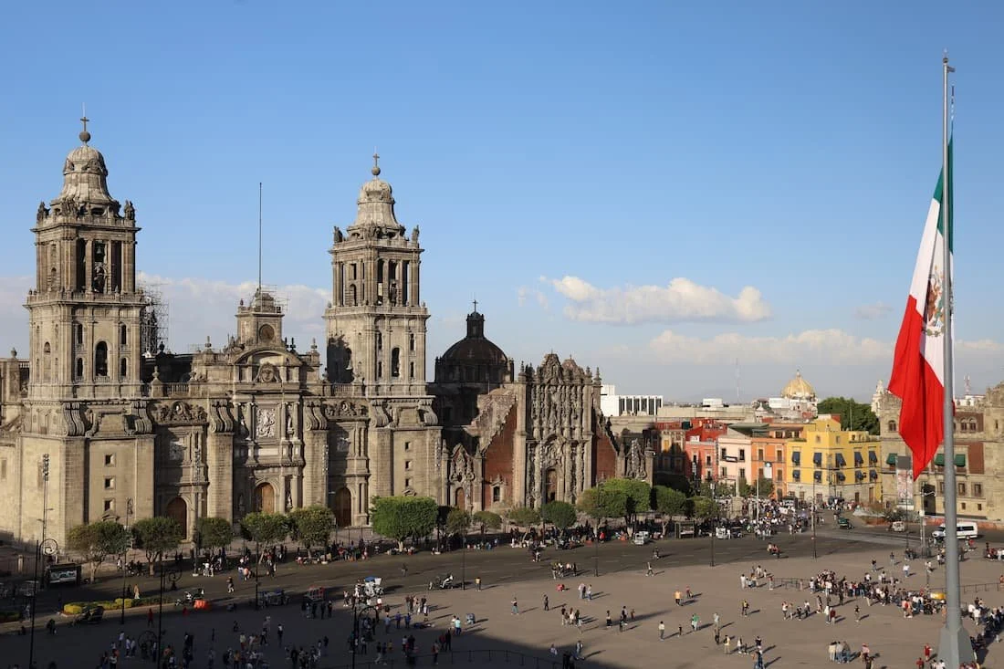 View of Mexico City’s Zócalo in Centro Histórico with the Metropolitan Cathedral and a large Mexican flag in the foreground