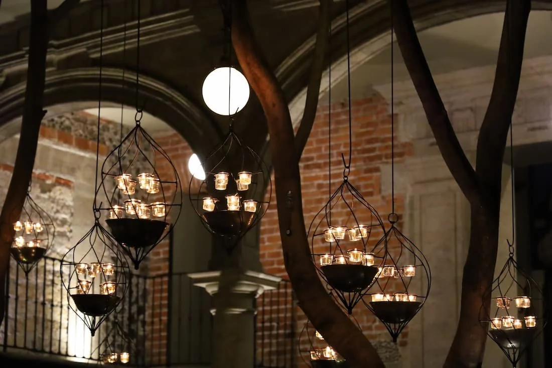 Hanging candle lanterns and warm lighting inside Azul Histórico restaurant with brick walls and tree-lined courtyard ambiance