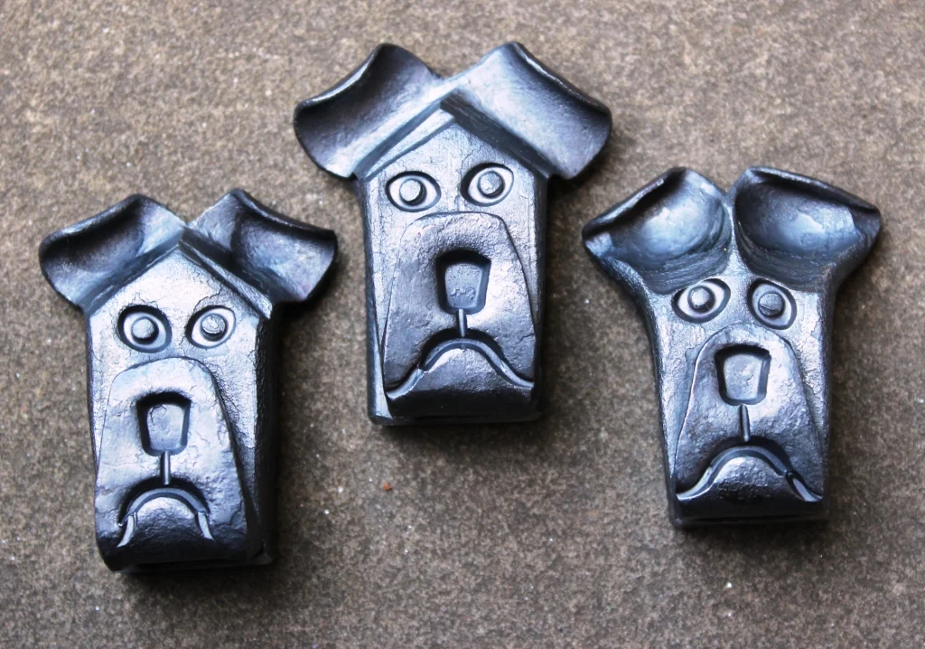 Forged dog head paperweights by Mick Maxen