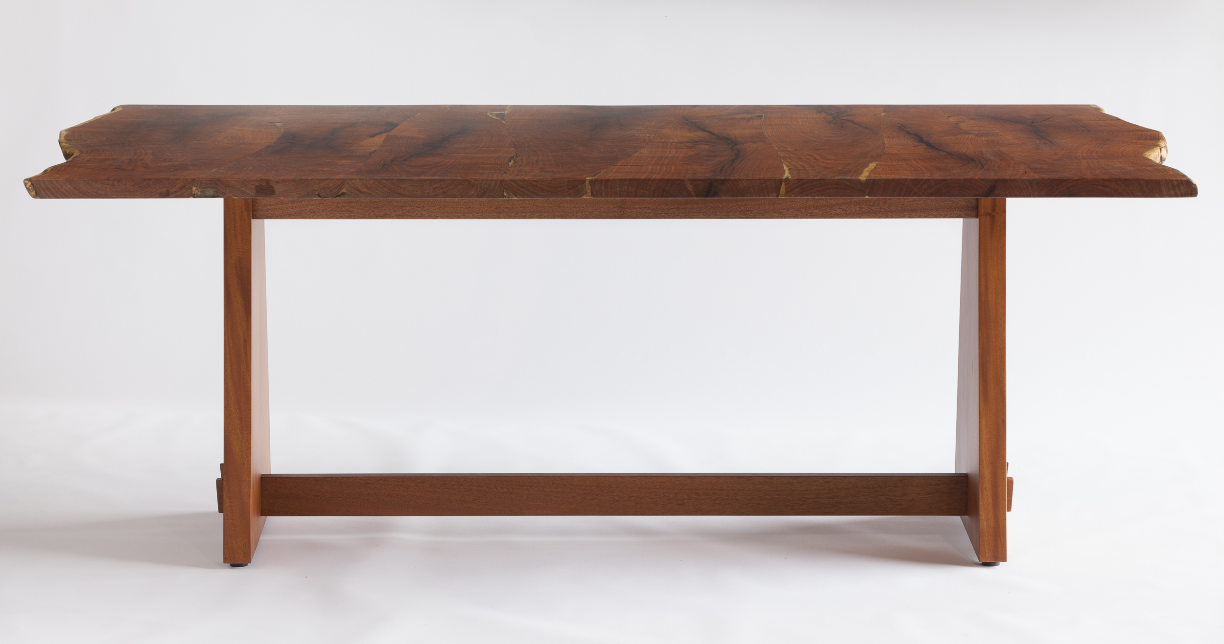This "live-edge" table features slabs hewn from south Texas mesquite. It displays a tabletop dimension of 79" x 42" and stands 29" high. The african mahogany base follows a more contemporary "trestle" design. Design by Reznikoff Custom Furniture