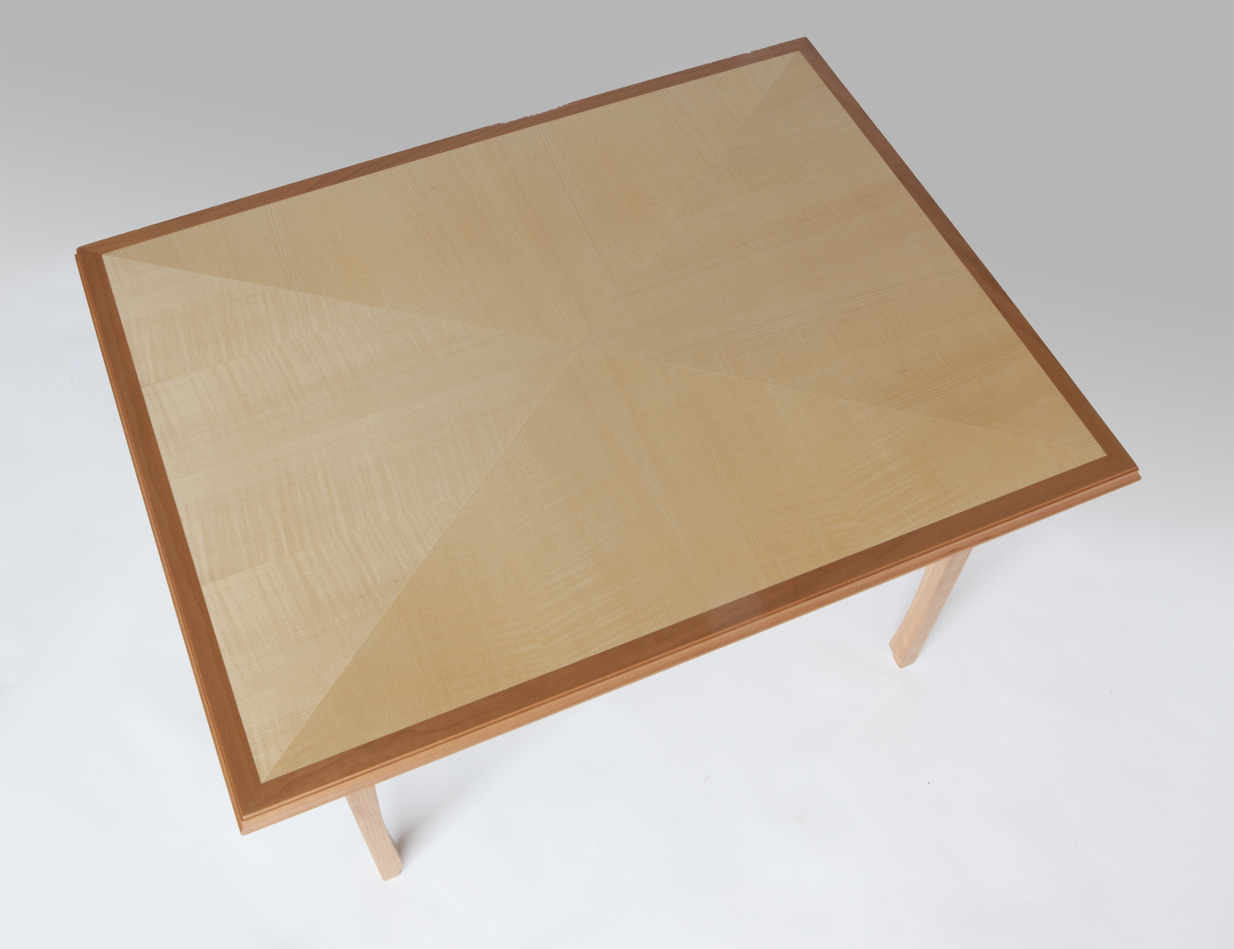 Coffee table of quarter figured sycamore, laid-up in the "reverse diamond" pattern with cherrywood edge, trim and base. Of note is how the reverse diamond pattern changes contrast with its angle to the light. Dimensions: 33" x 25" x 20" high Design by Reznikoff Custom Furniture
