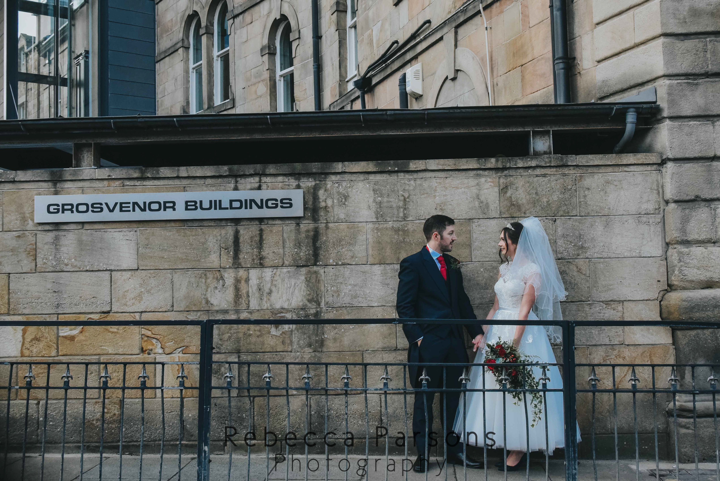 bride and groom standing against wall