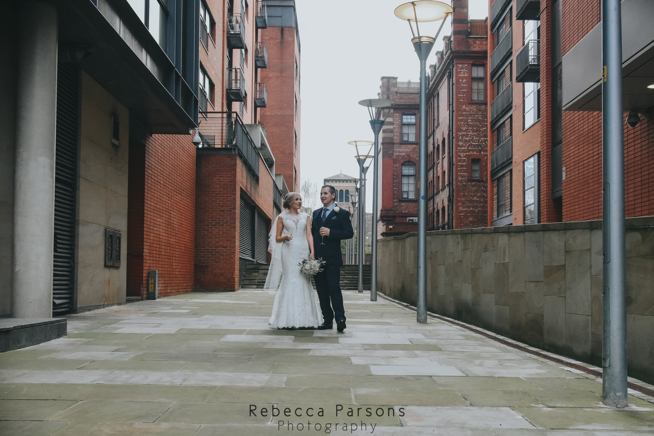 bride and groom walking between buildings in Manchester