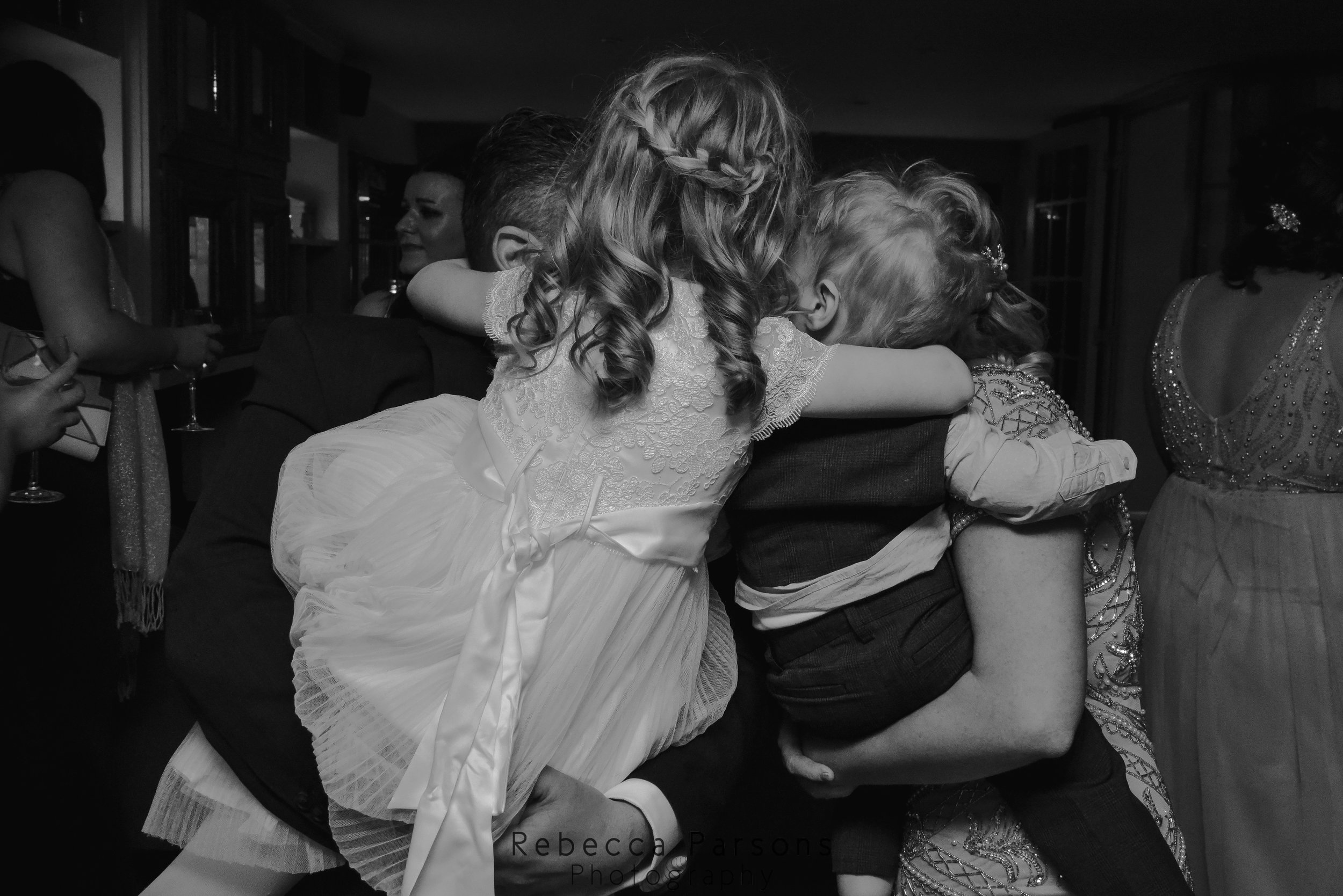 family hugging on dance floor black and white