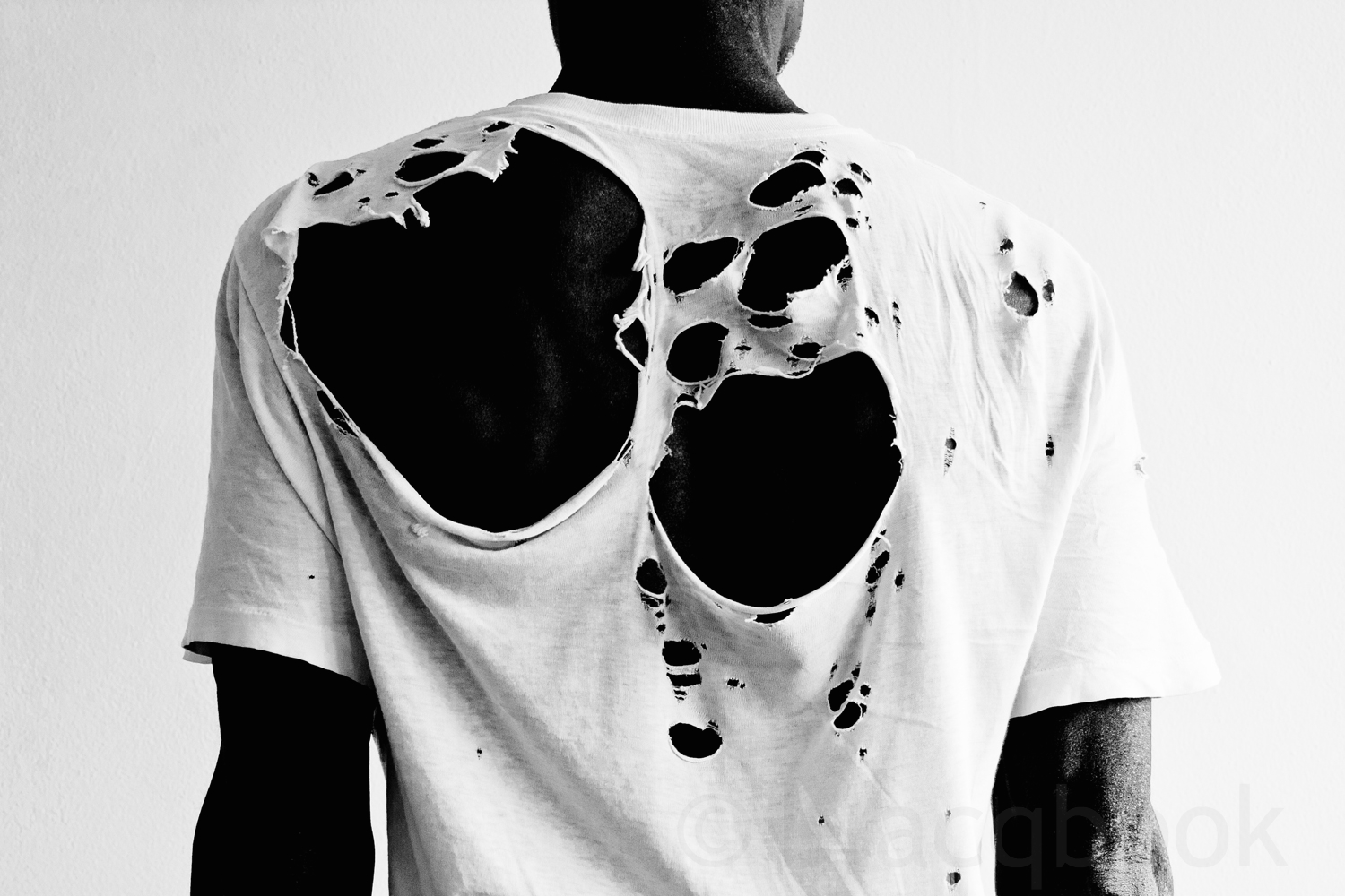 back of a man wearing a naturally distressed white t-shirt with fashionable...