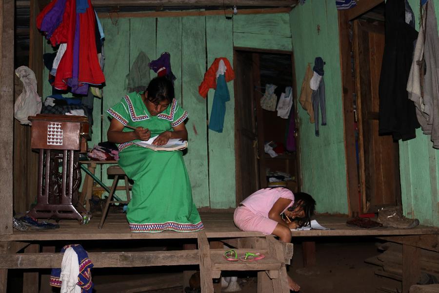 Agripina and her daughter use the last natural light of the day to finish their homework.