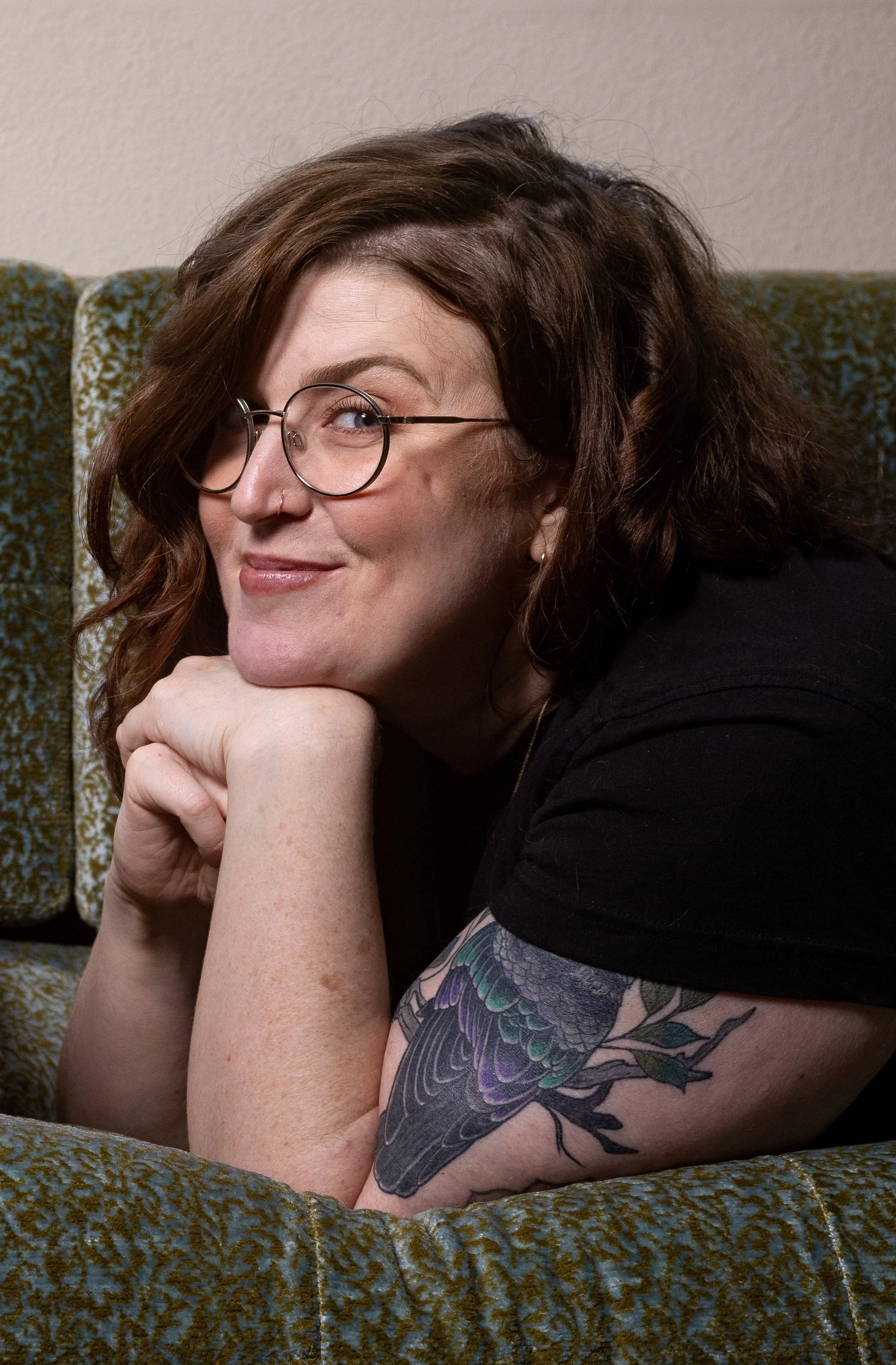 A three-quarter-profile photo of the writer Devon Maloney, smiling with her head on her hands.