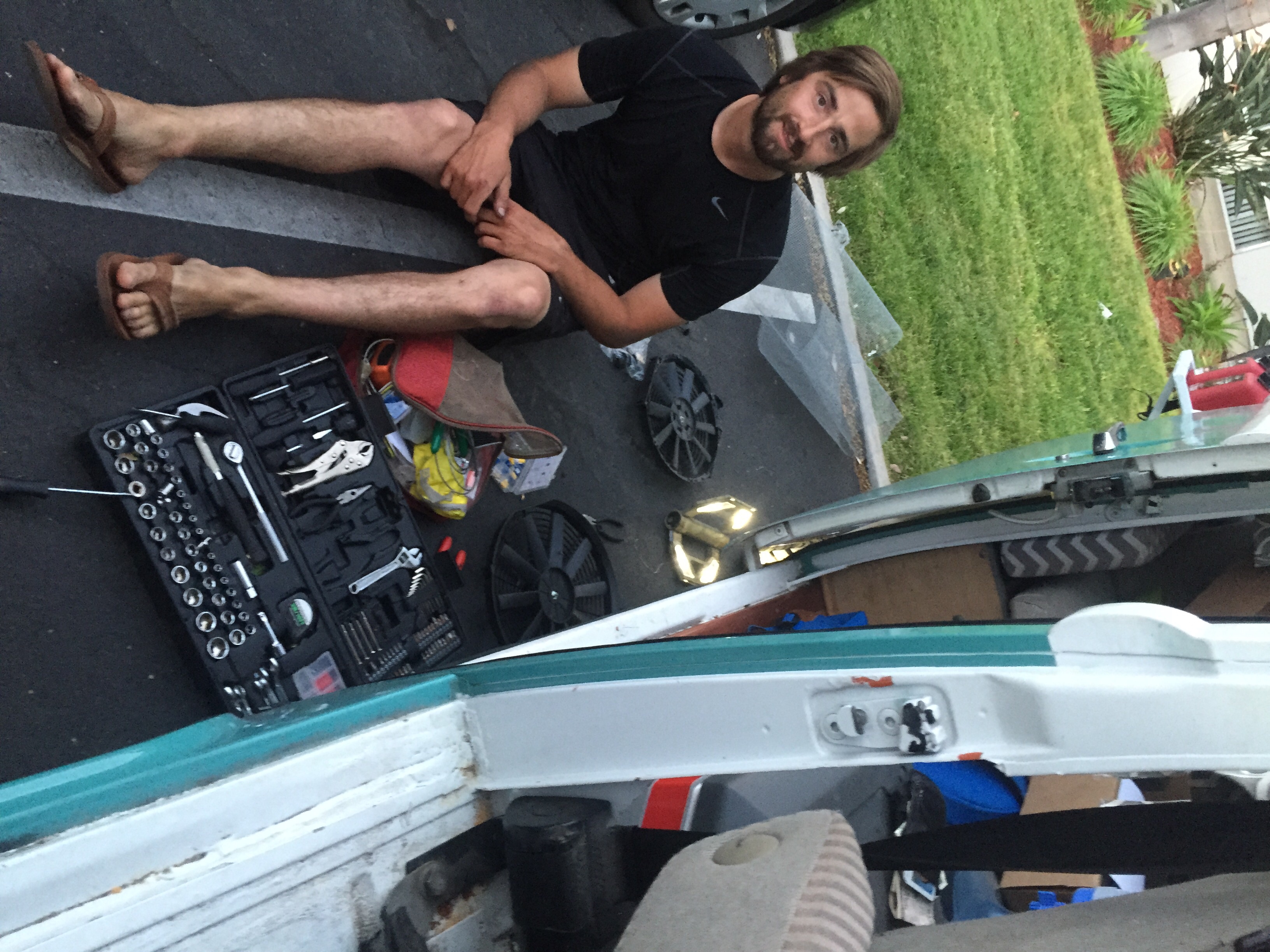We've grown accustomed to working on the bus in parking lots. No shame in the game. Here Dillon is upgrading a 10" fan to a 14" on the below the belly radiator.