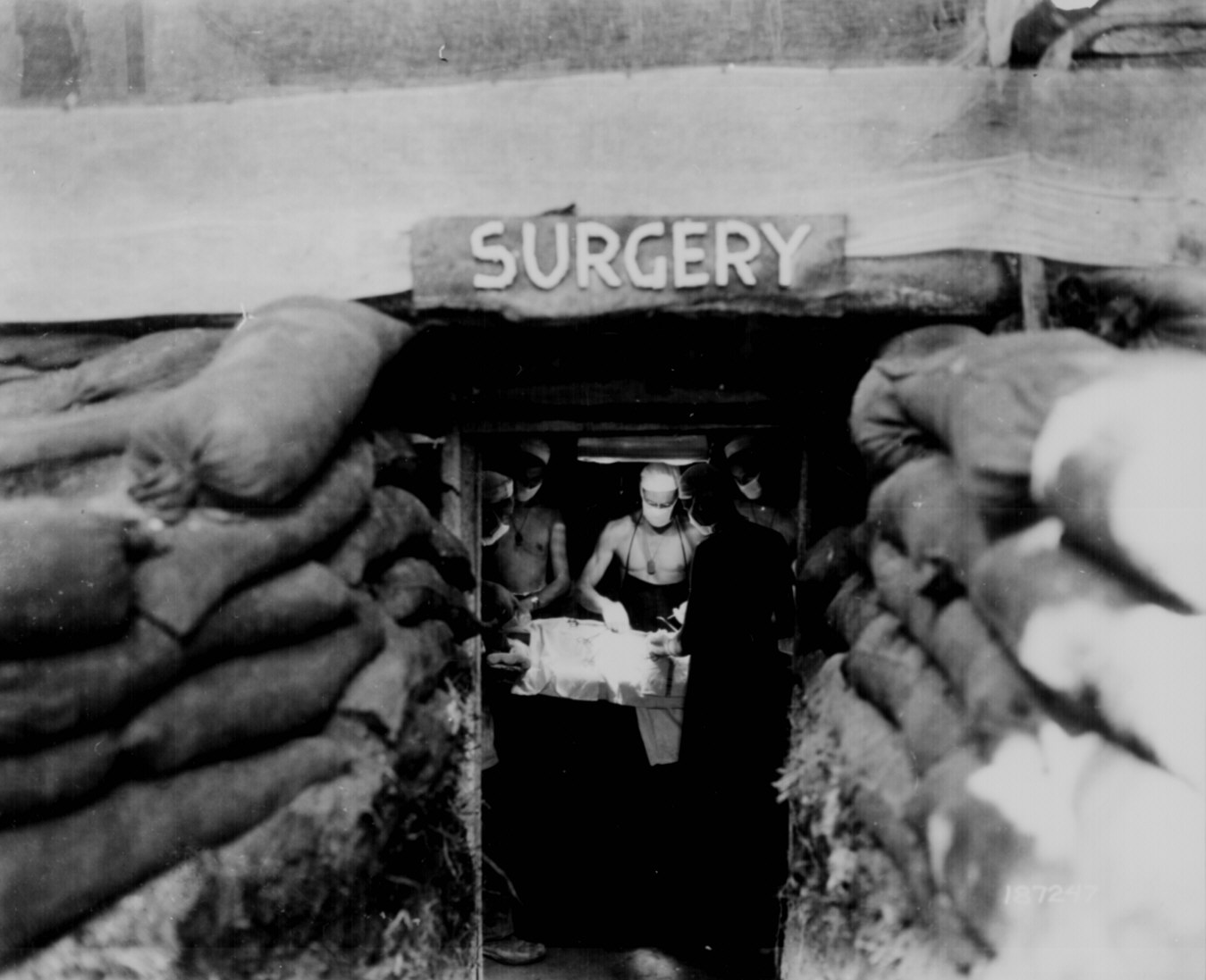  In an underground surgery room, behind the front lines on Bougainville, an American Army doctor operates on a U.S. soldier wounded by a Japanese sniper.  12-14-1943 