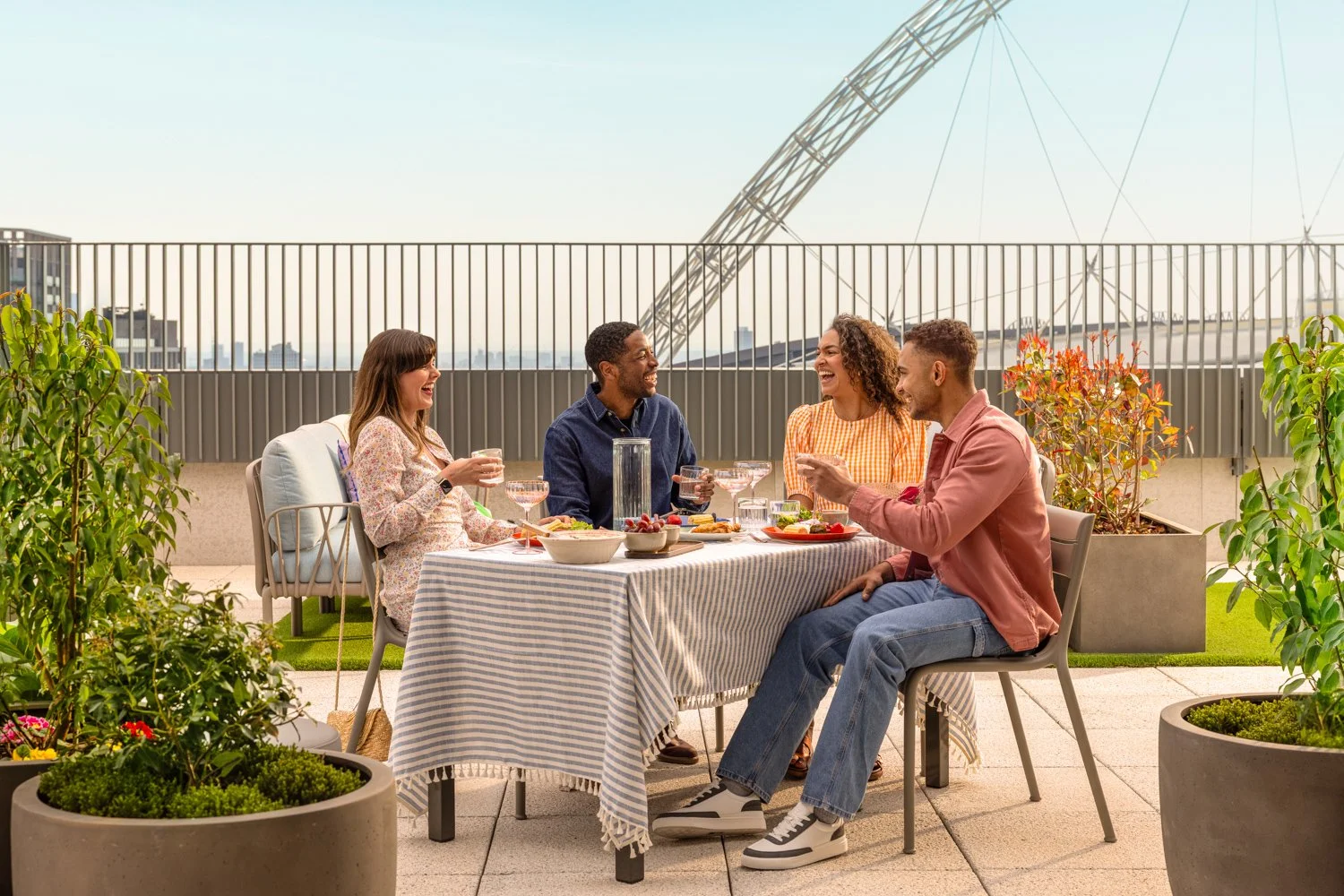  Friends enjoy dinner and drinks on the roof top in the sun 