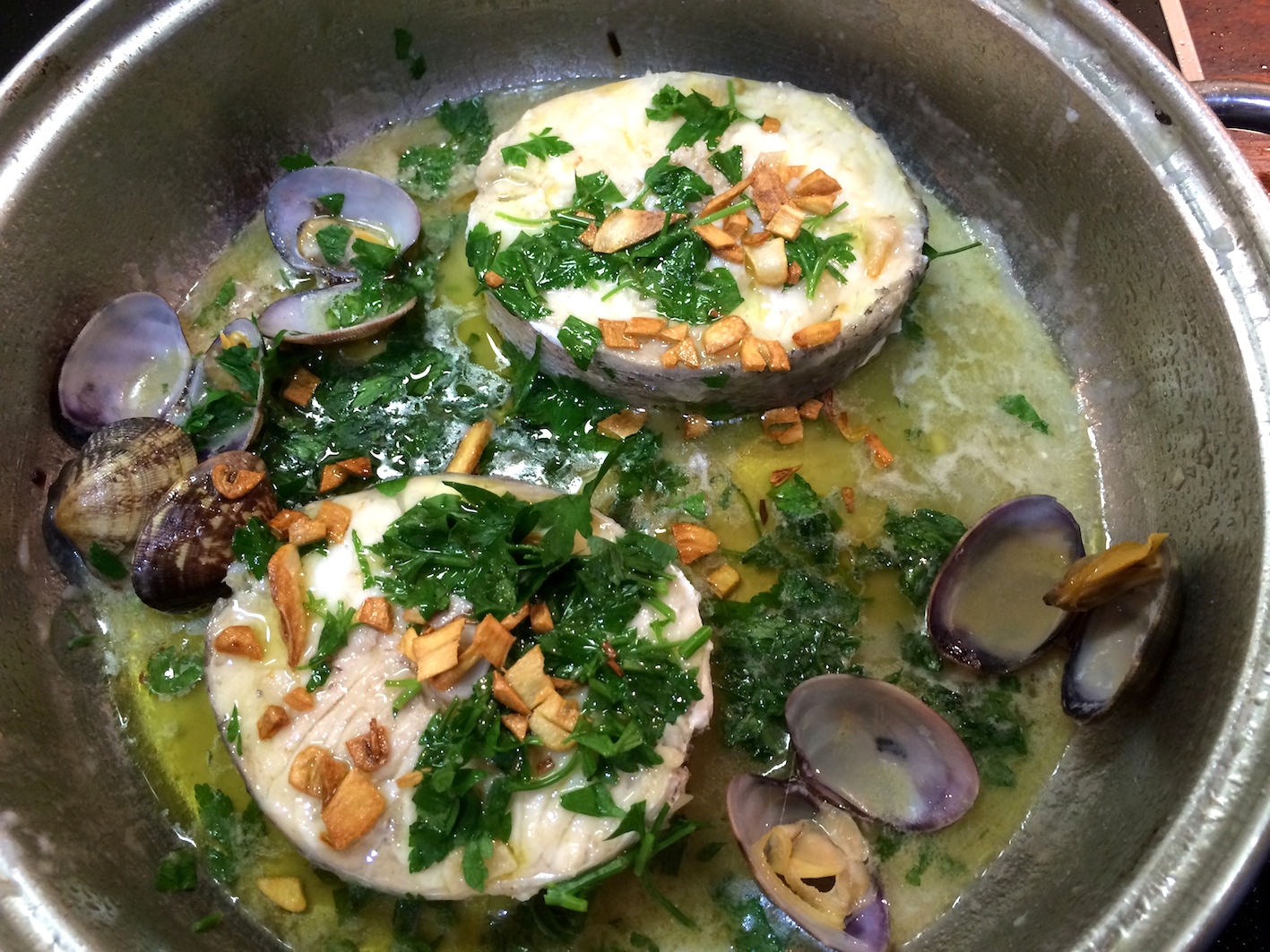 Cooking hake in garlic sauce with clams
