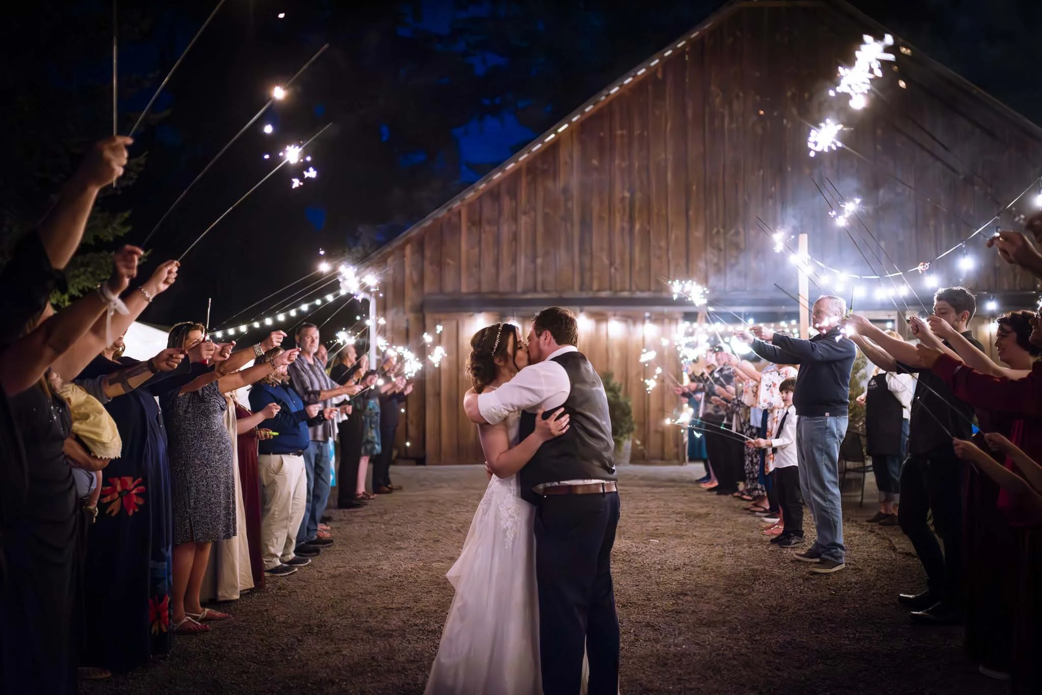 A bride and groom kiss with a sparkler exit at their wedding