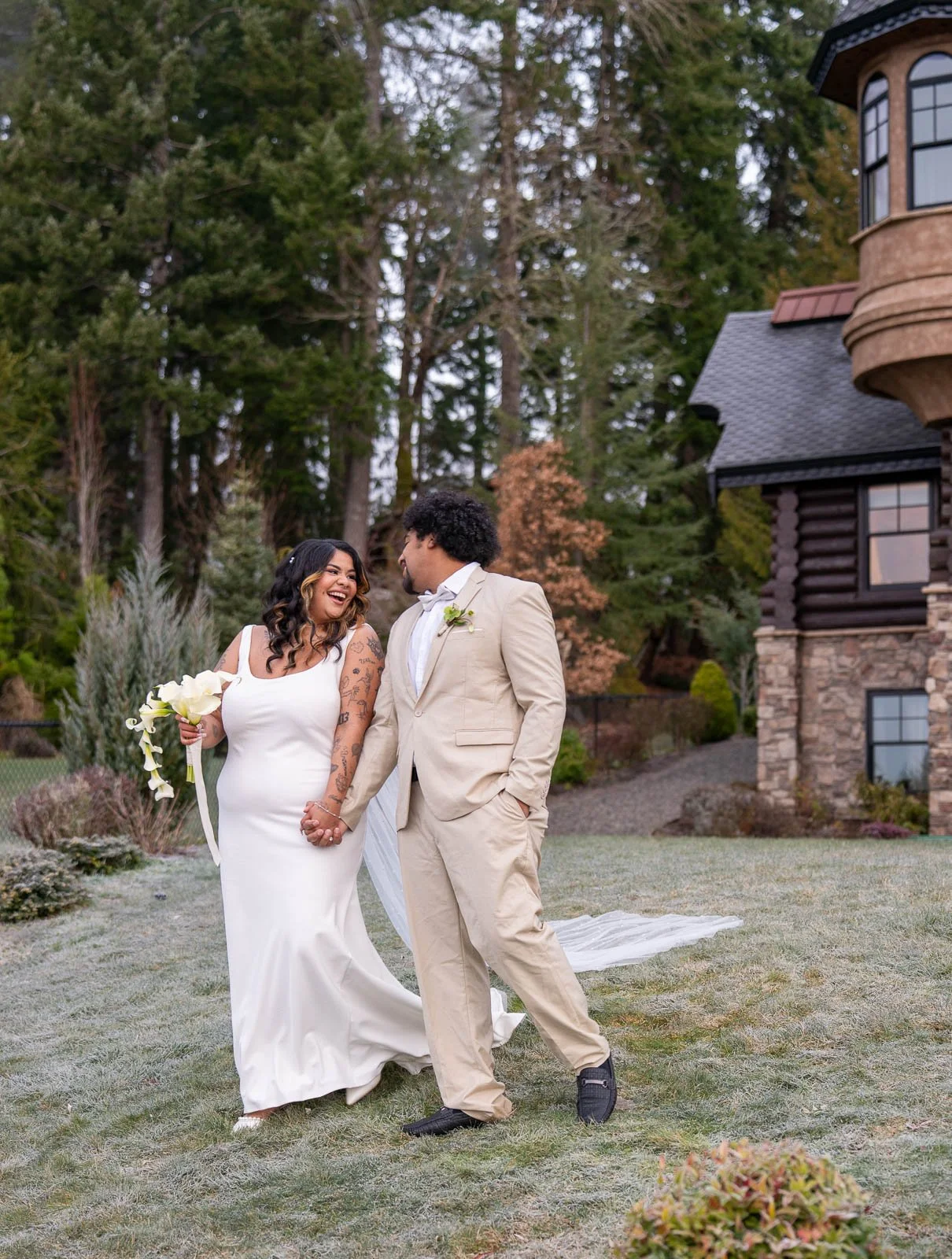 Bride and groom walking together near the castle's stone turret, both laughing