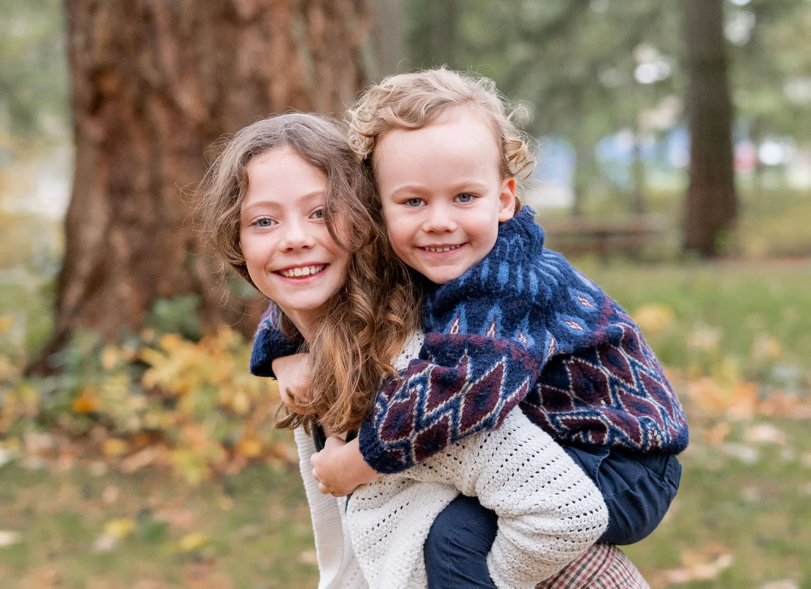 Brother riding on his sister's back during a playful outdoor family photo session in Olympia, WA.