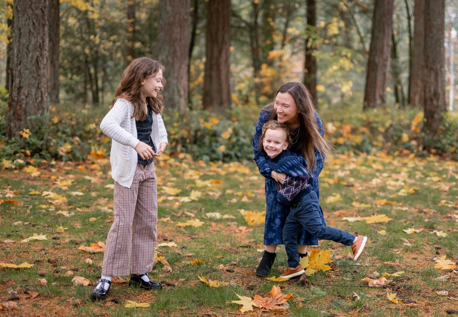 Mom laughing and playing with her children during a candid fall family photography session in Olympia, Washington.
