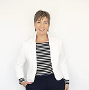 Woman smiling, wearing a white blazer over a striped shirt, with short hair