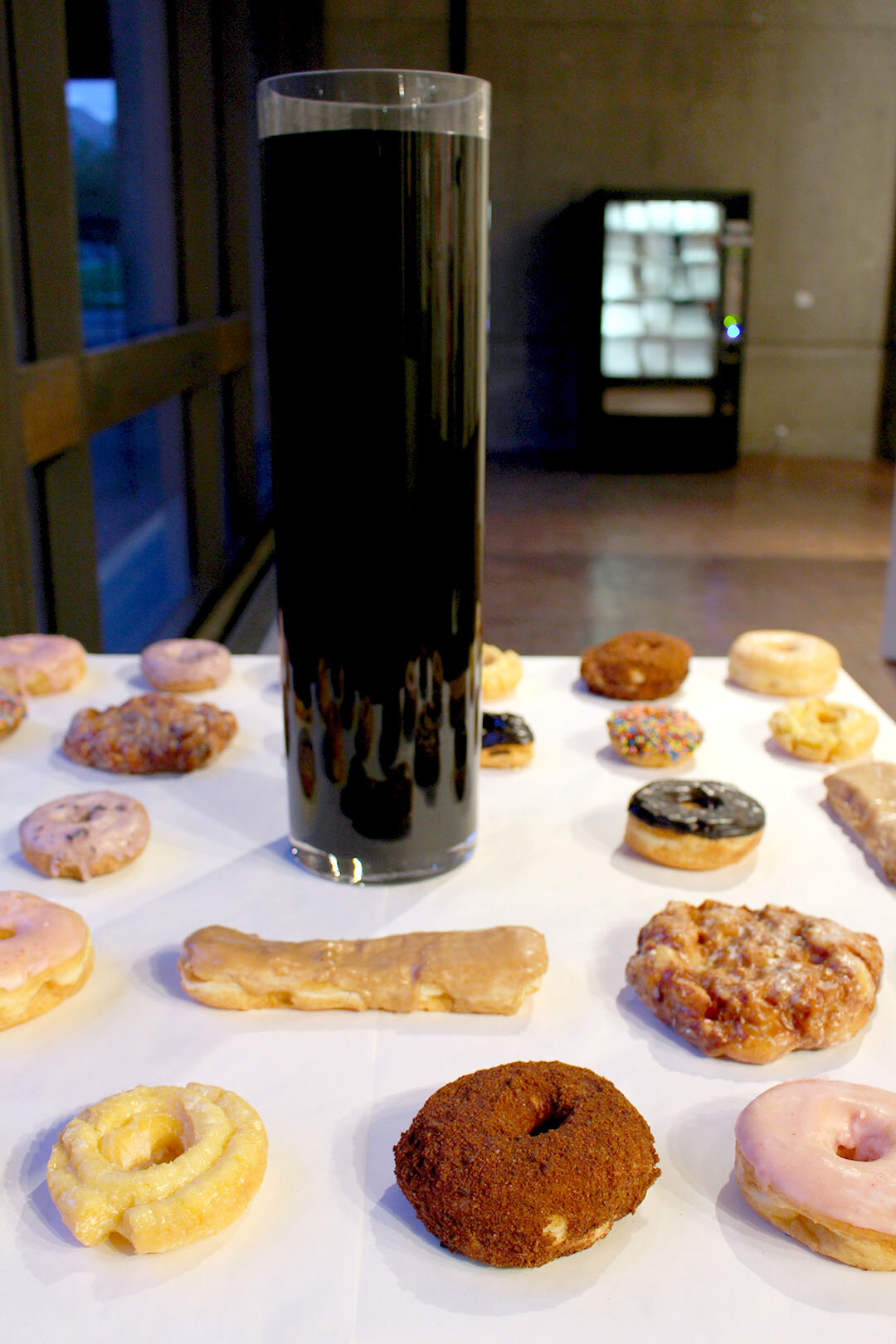  Sunny and Blue Skies with a 15% Chance of Cross Contamination. 2016. Donuts, glass cylinder, black lemon curd with ascorbic acid. Varying dimensions.  