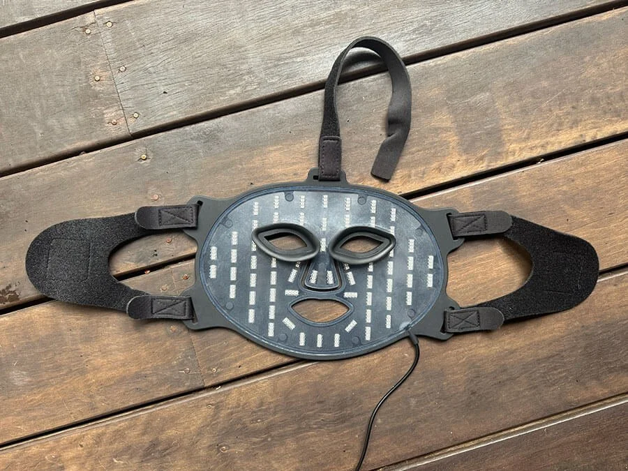 bon charge the best red light therapy mask laying flat on a table to show how the u shaped straps and top of head strap works