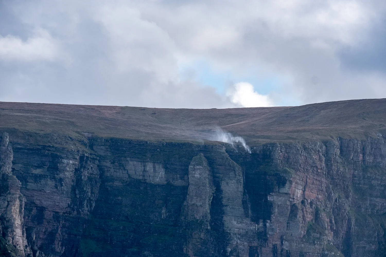 White smoky patch is not smoke but a waterfall, which with Force 8 gale winds is being blown in reverse back up the waterfall