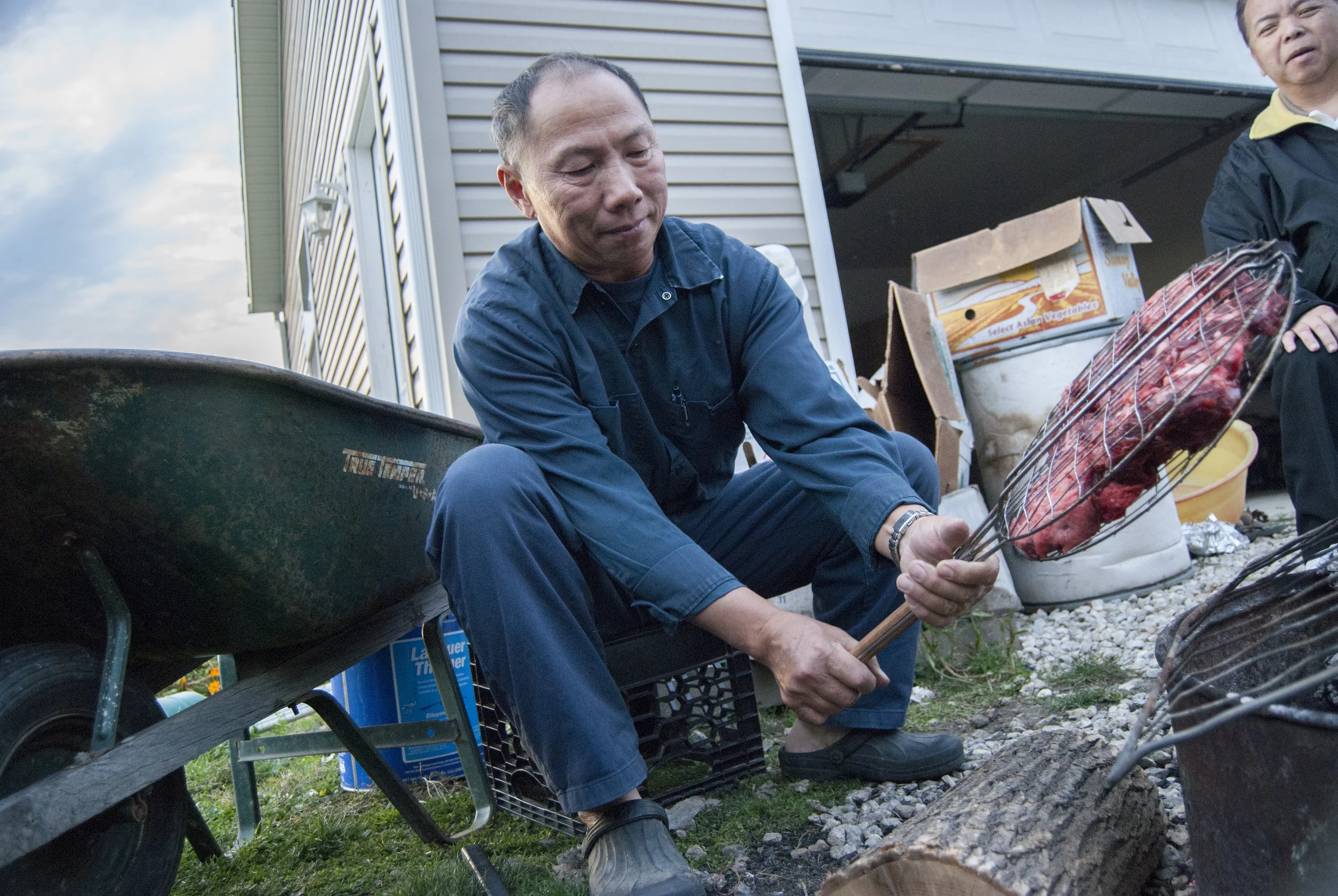  Pastor Que looks on, telling stories while True cooks fresh deer meat over a fire. True connected three 3x4 foot slats of wood funneling against the direction of the wind in order to control the fire. The Yang's recycle many objects, each one seemin