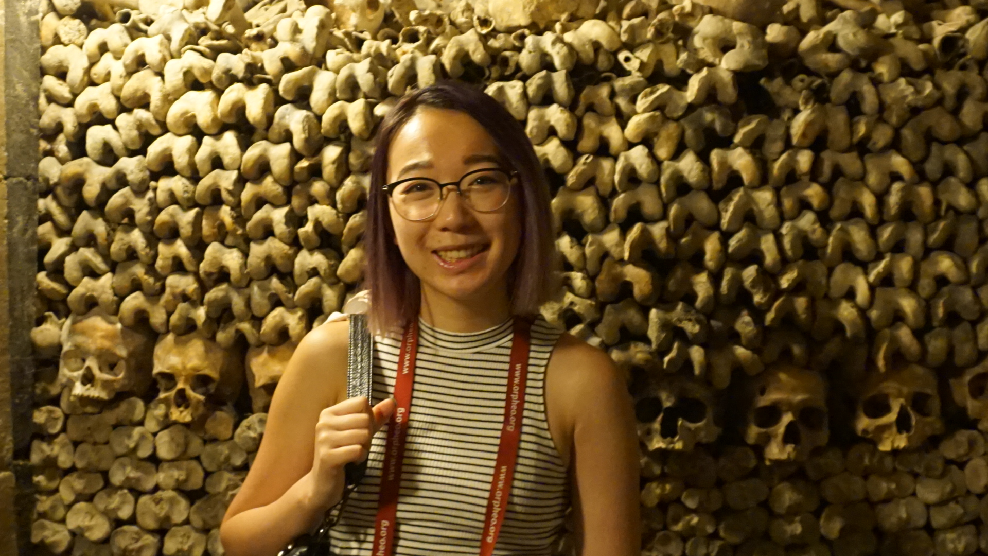 Jenny standing in front of human skulls and bones found in the Paris catacombs.