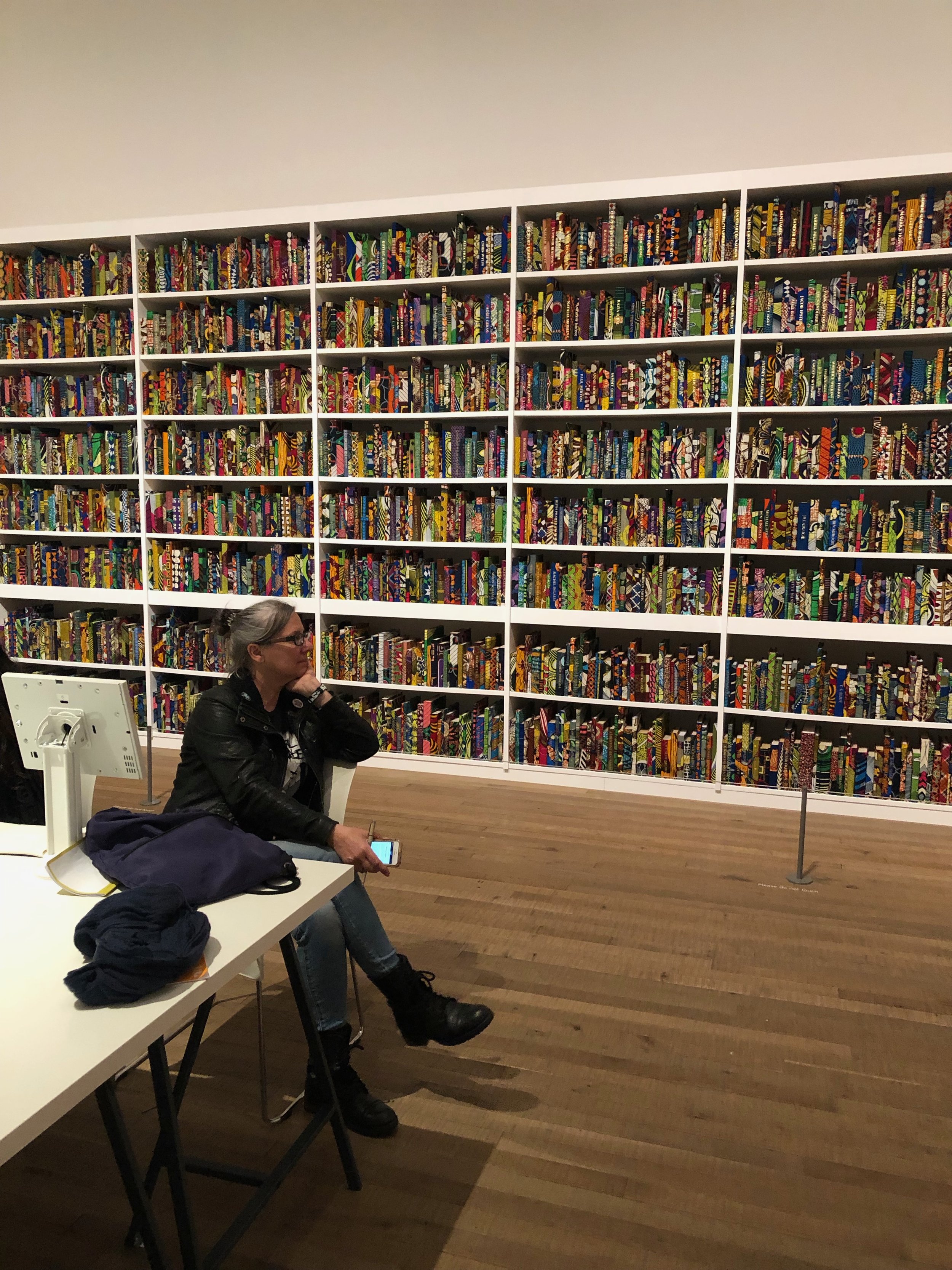 Angela sitting and enjoying her assigned artist’s installation at Tate Modern— Yinka Shonibare’s British Library (2014)