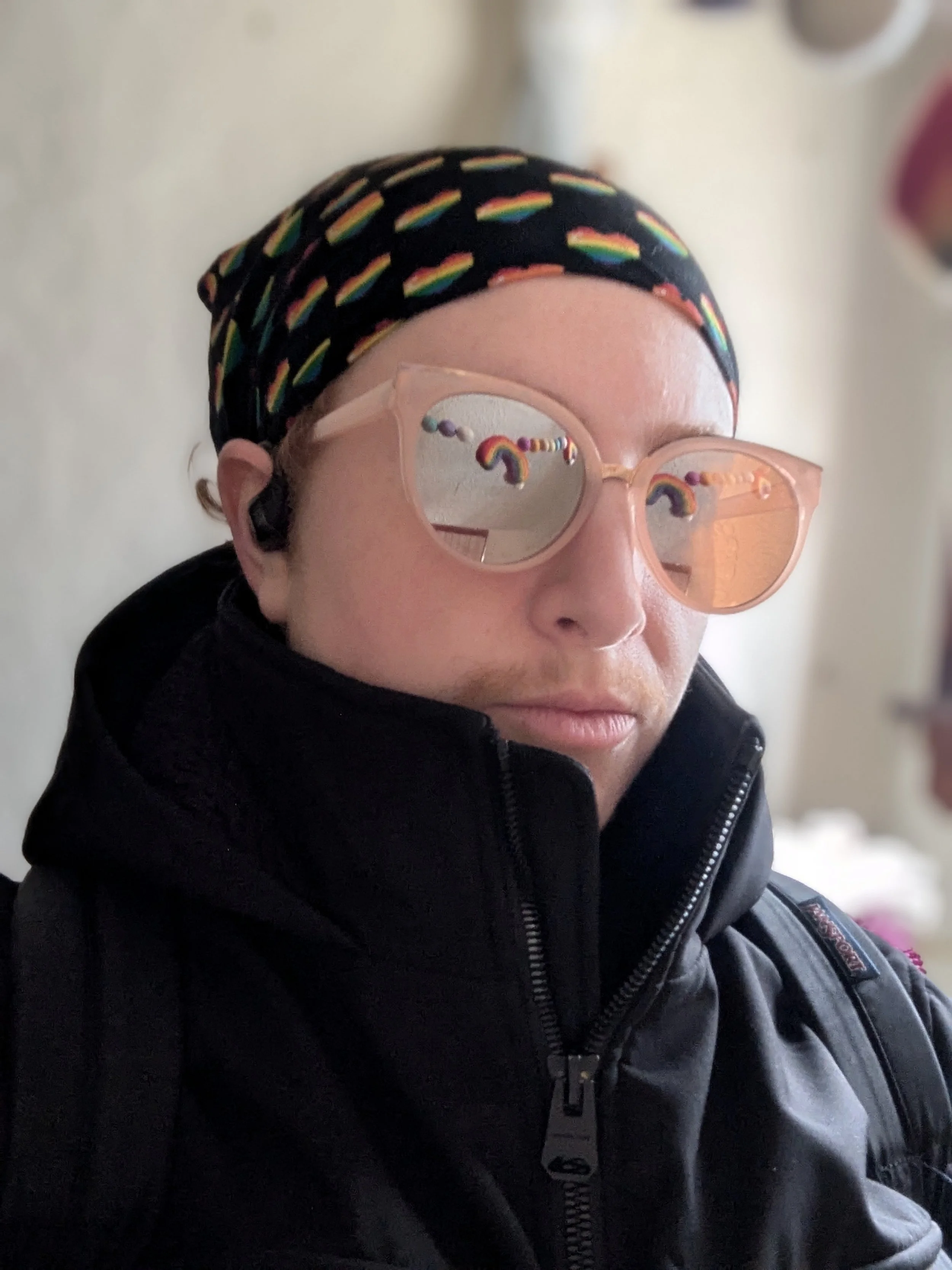 Jesse during Pride Month, wearing a bandana with rainbow hearts and sunglasses reflecting rainbow decorations.