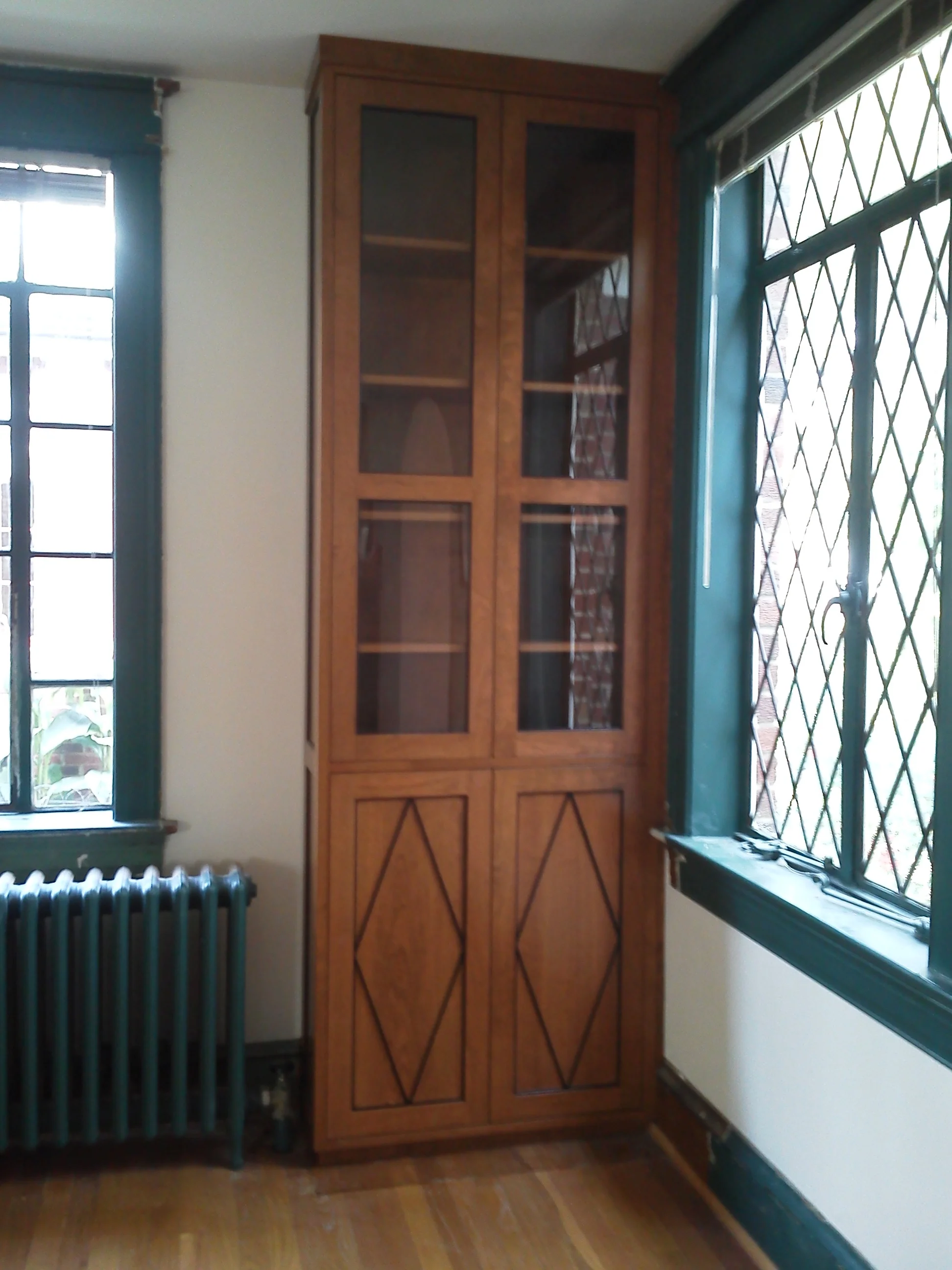 Cherry cabinetry with diamond pattern to match leaded window.