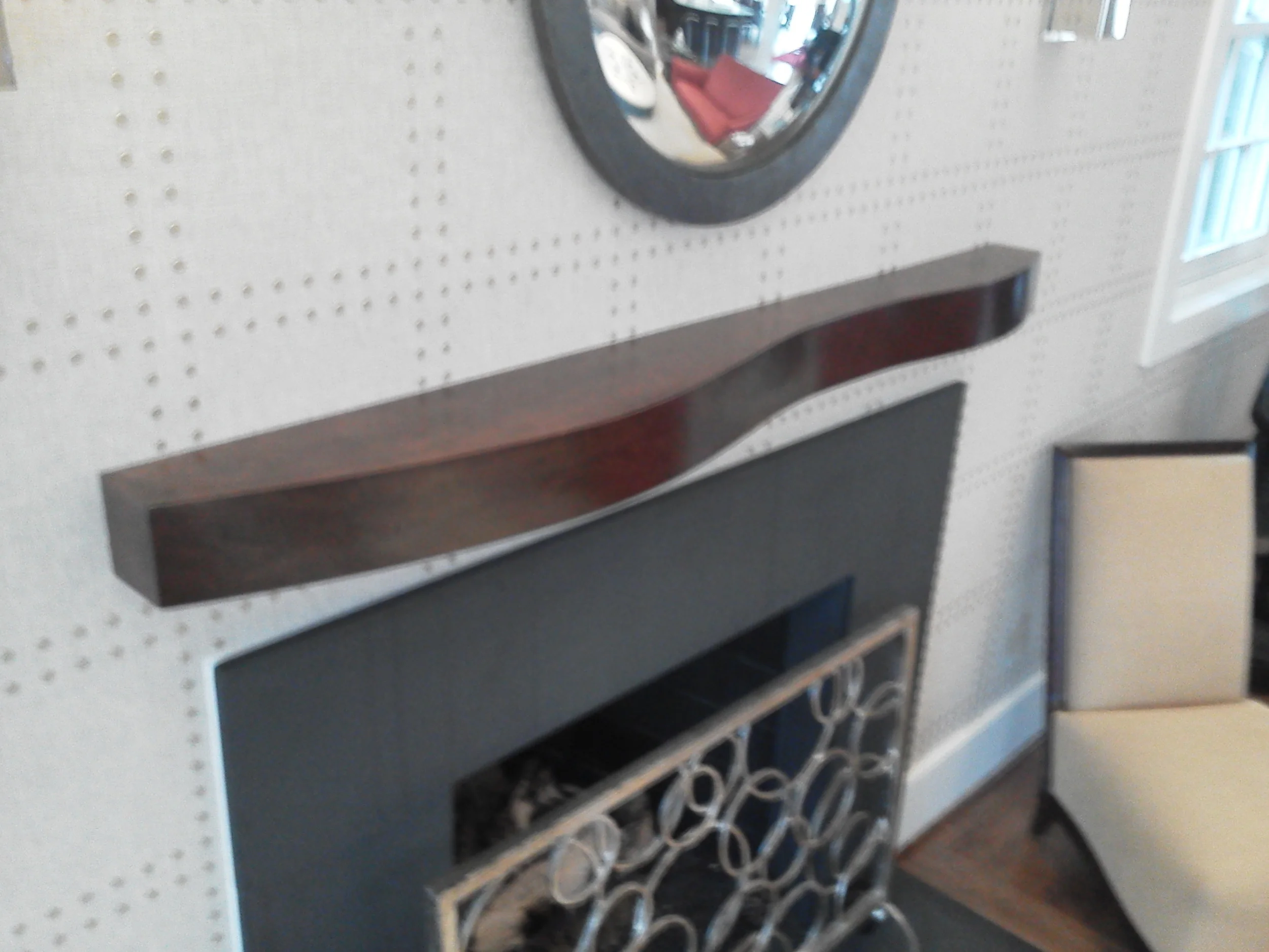 Floating cherry mantel on upholstered wall.