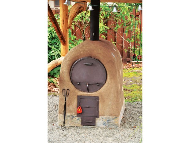 A barrel oven pictured in the book, finished with cob plaster.