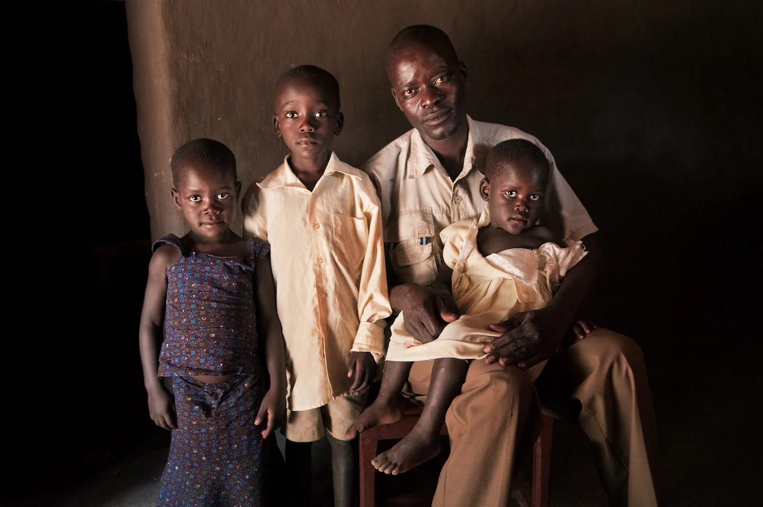 Valente Inziku with his children Patricia Alezuyo, Joshua Tabu, and Convert Diana at their home in Aribio village, Arua District, Uganda (for The New York Times).