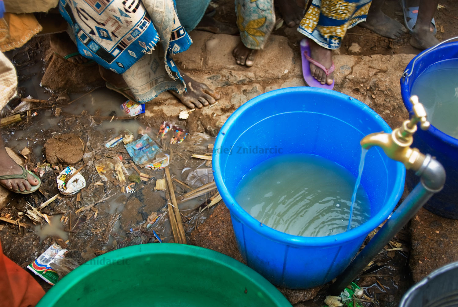 Water from a water-well which is located less than a hundred yards from the nearby open dump site runs into a bucket. Well-water like this is found in many neighborhoods of Kano and is used by residents for washing dishes, clothes and bathing.