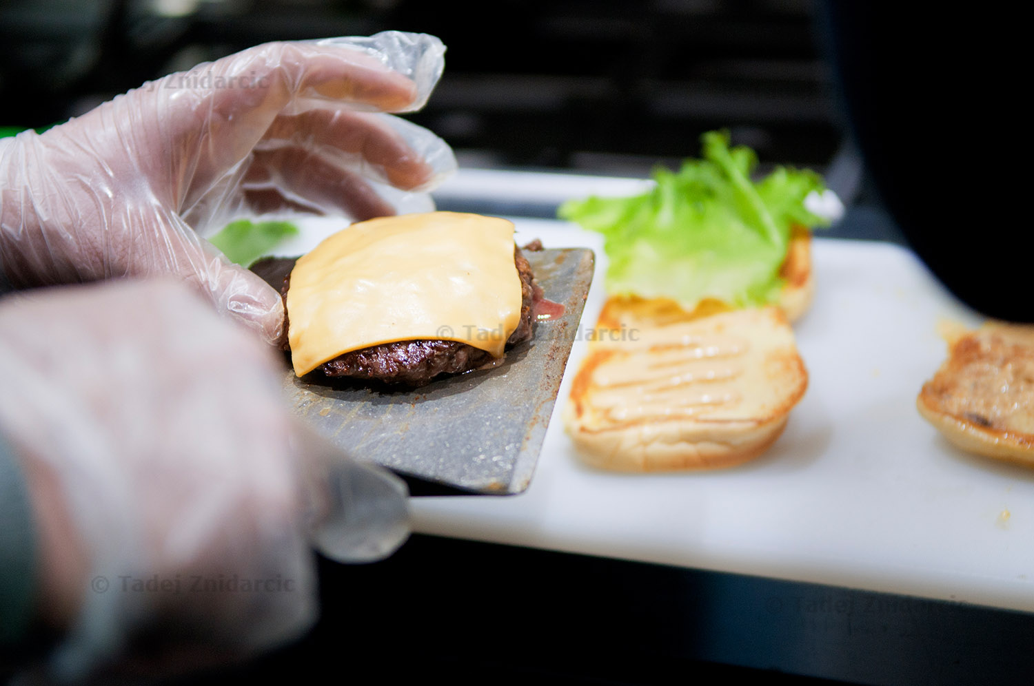 Cook prepares a burger at Burger Heights on Wadsworth Ave.