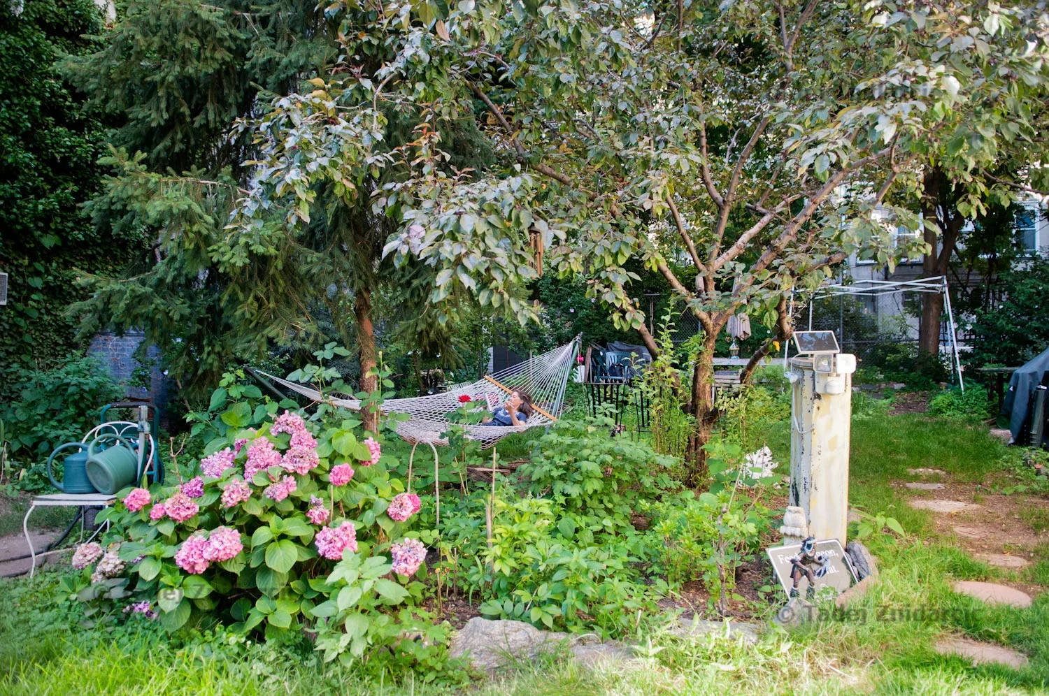 Elizabeth Ruf-Maldonado lays in a hammock and reads in De Colores Community Yard Garden on E 8th street in East Village, NYC.