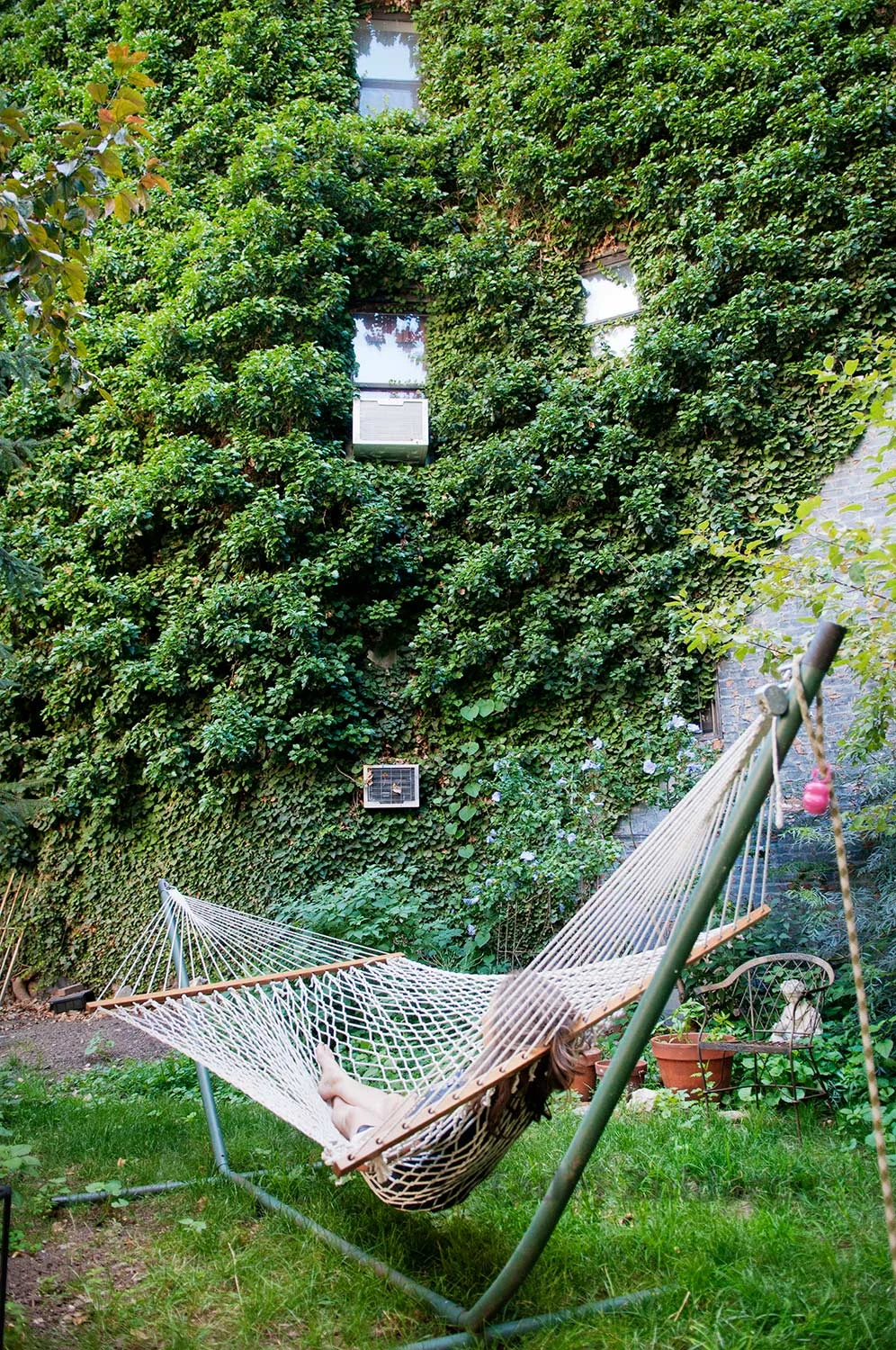 Elizabeth Ruf-Maldonado lays in a hammock in De Colores Community Yard Garden on E 8th street in East Village, New York, USA.