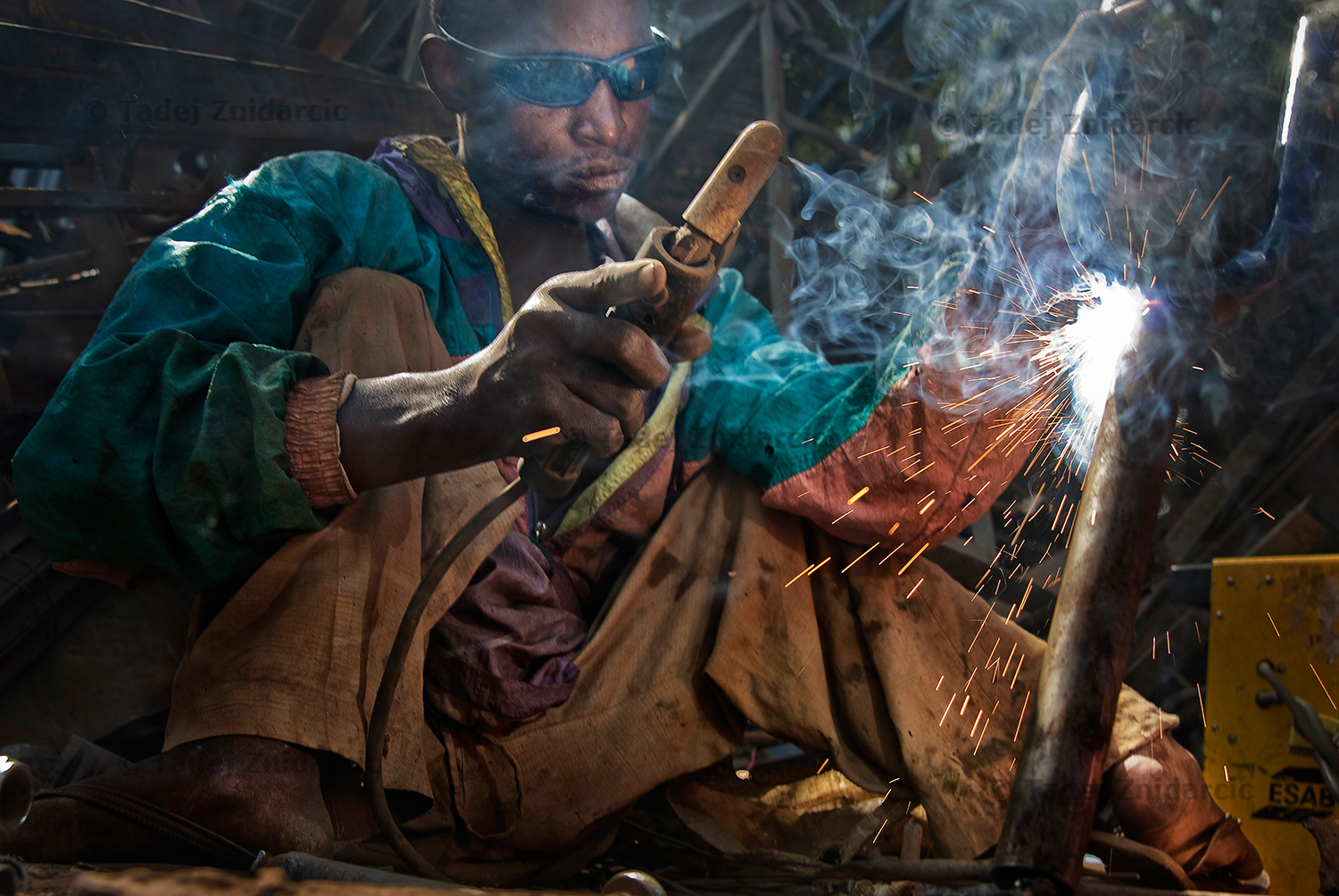 Sani Abdullahi welds together parts of bicycles. He works in the welding workshop where he transforms bicycles into hand-operated tricycles for use by polio victims.