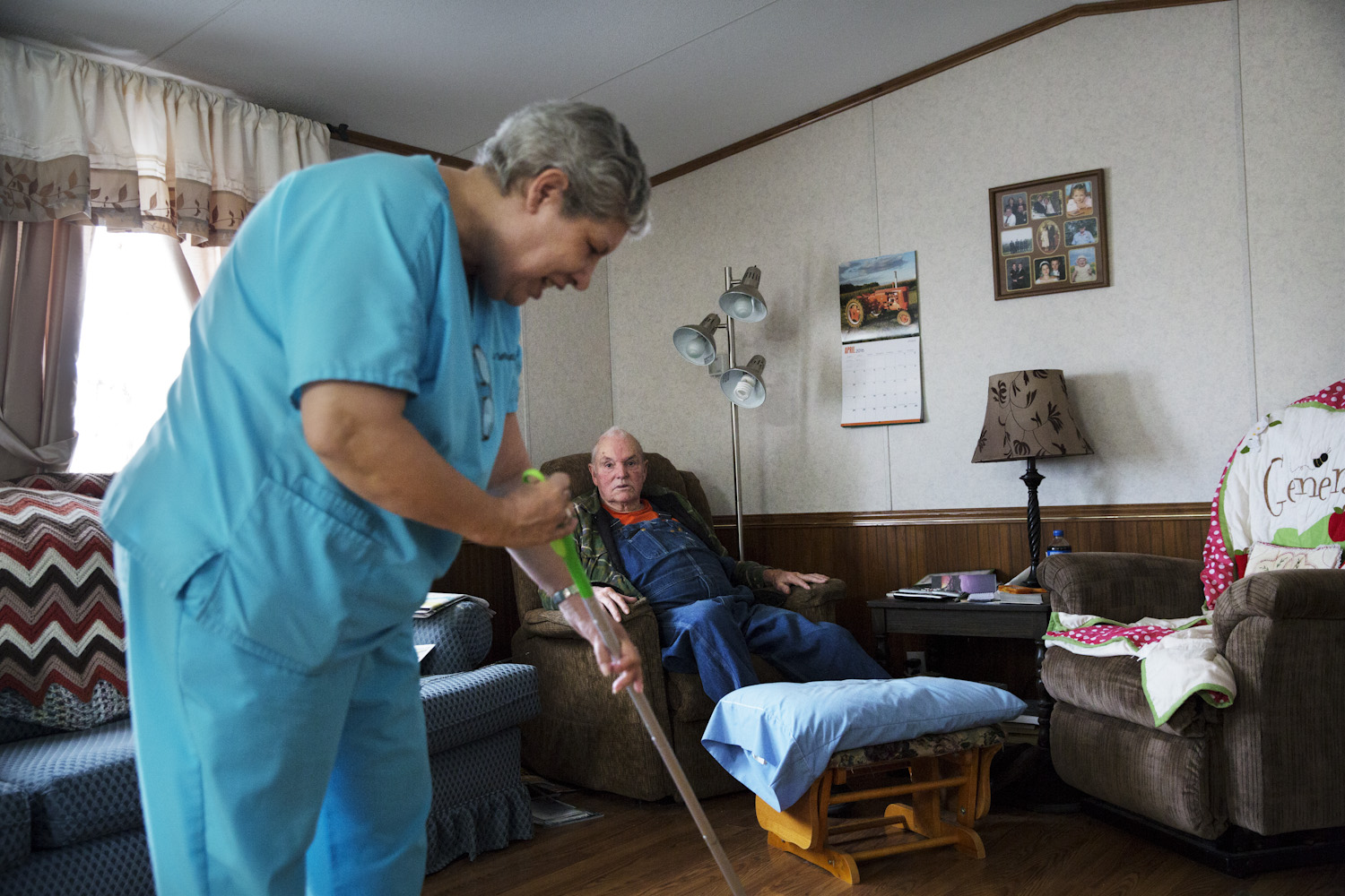 Home care aide Diana chats with Walter while cleaning the floor of his home.