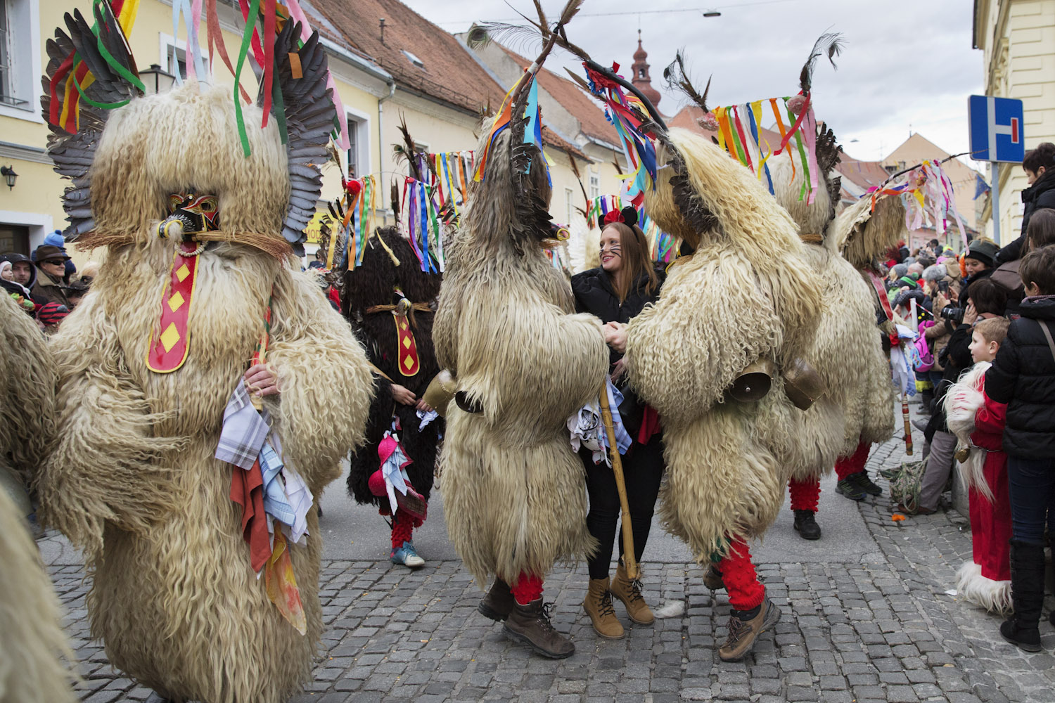 Korants jump with a girl during The International Carnival Parade in Ptuj. During the Parade korants continuously choose girls watching the Parade, bring them into the parade and then jump with them. Afterwards girls tie handkerchiefs on their ježevka, a wooden bat with hedgehog spikes that korants used to use as a weapon.