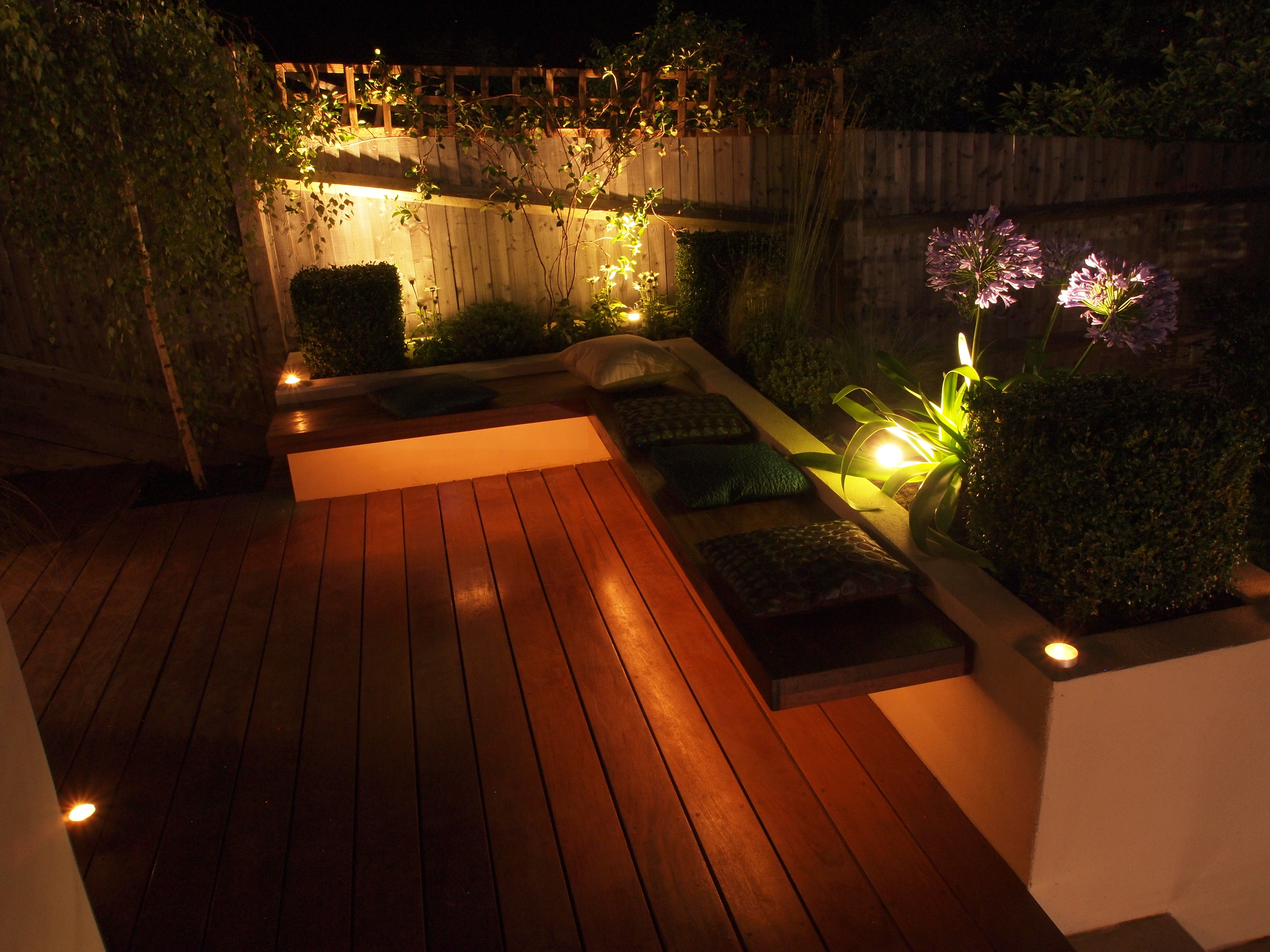 Seating area and border plants in garden makeover N10 at night