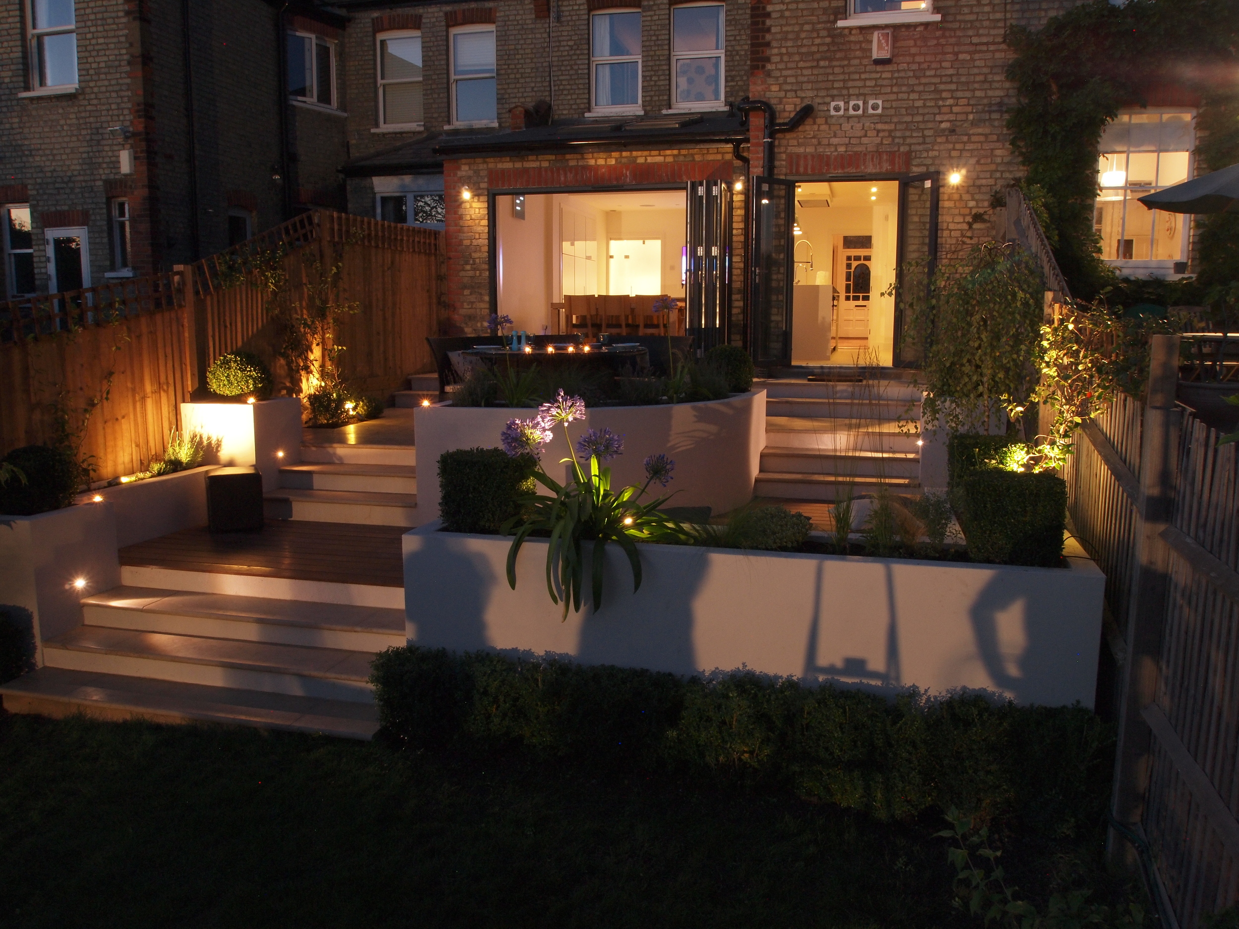 Terraces lit up at night in a North London garden designed for a family