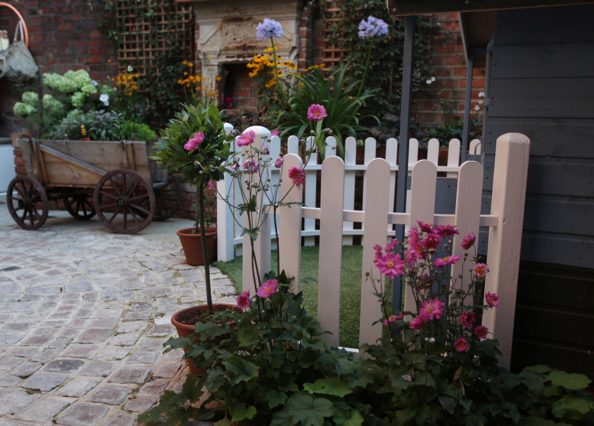 Fun garden design in North London with white picket fence and hand cart