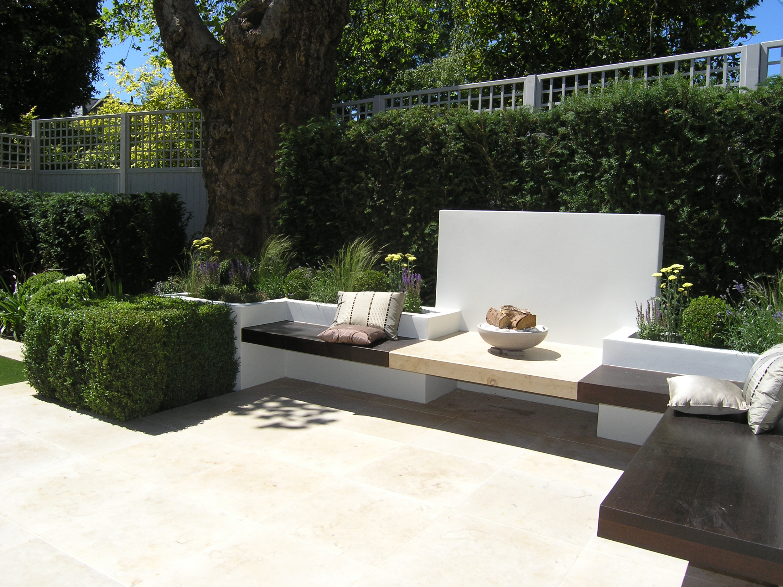 Hardwood benches and limestone patio in low maintenance garden design N6
