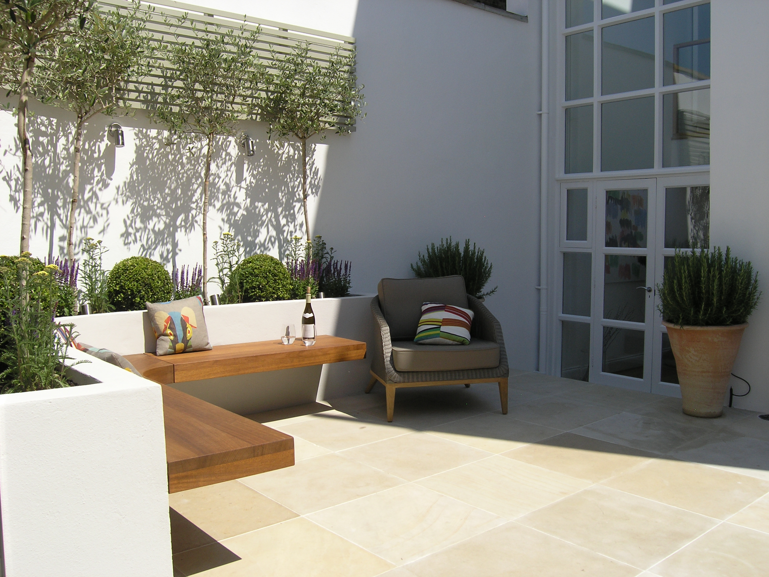  Small London courtyard garden landscaping ideas with limestone patio and hardwood benches. 