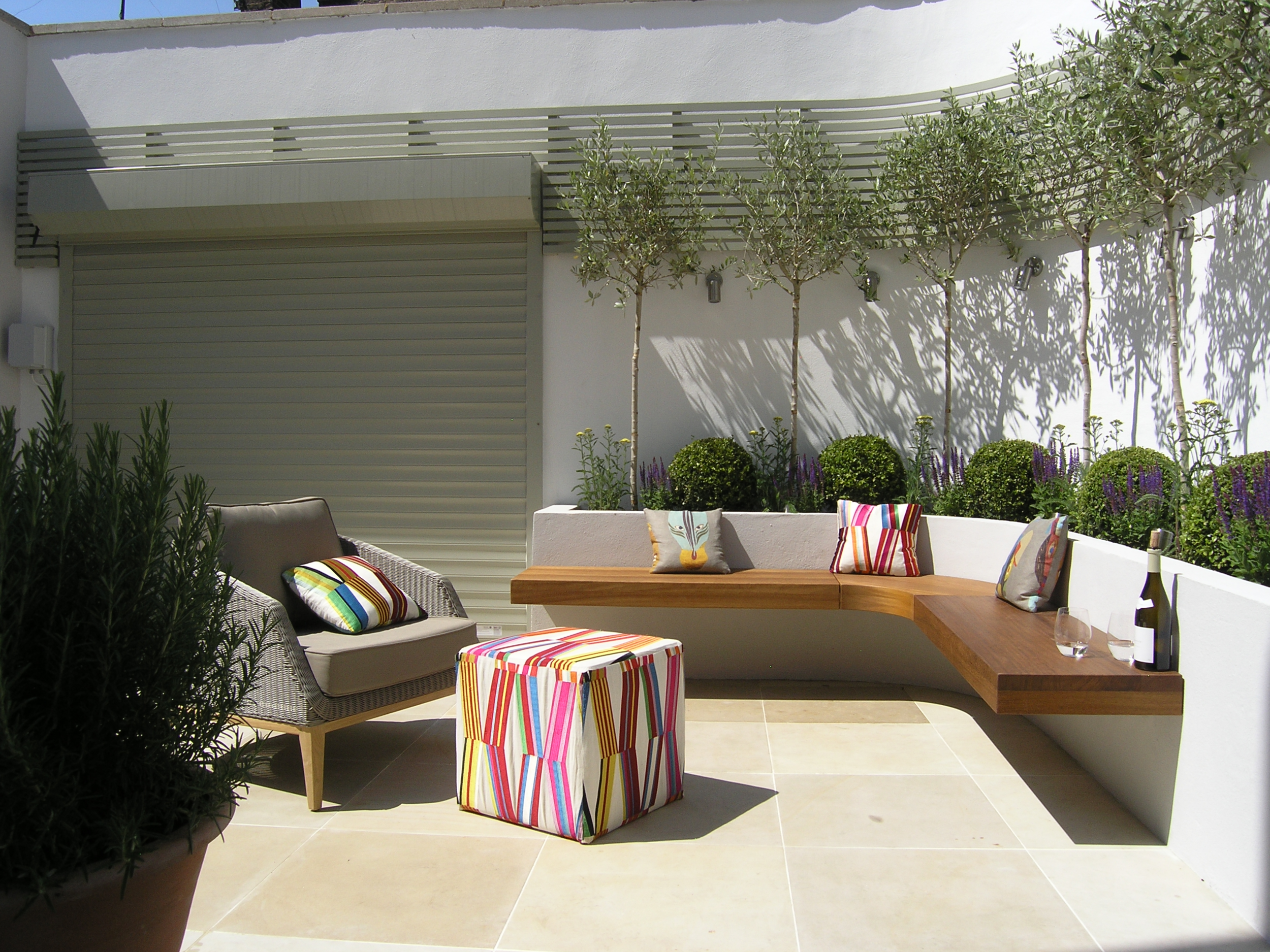 Curved wall in London garden makeover with sandstone patio and floating benches