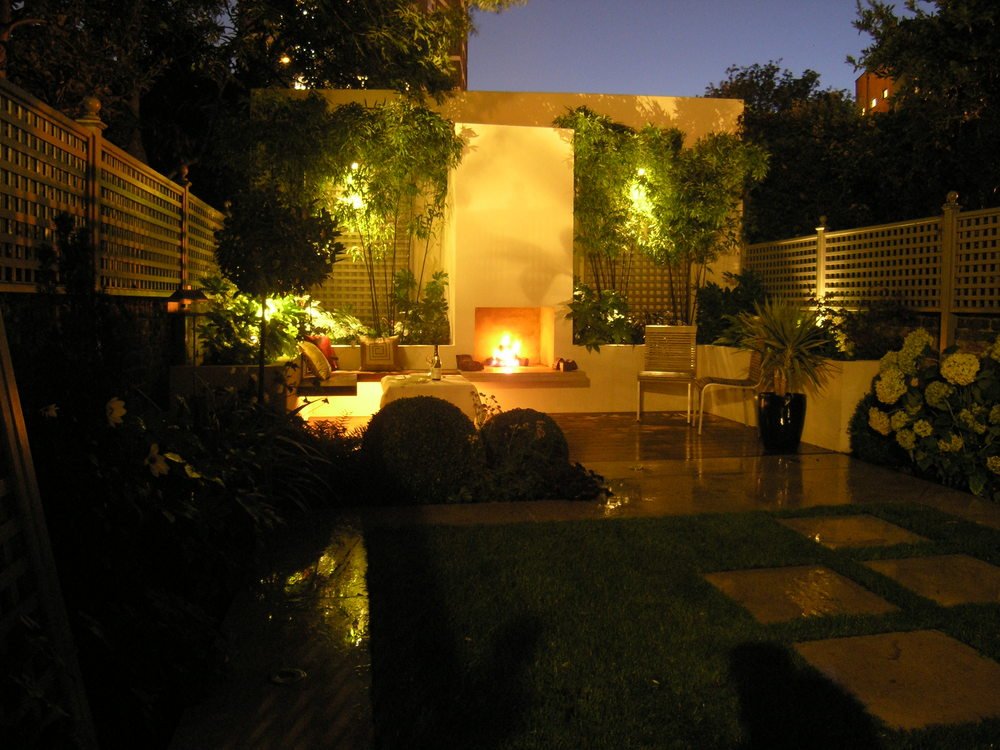  Modern garden design in Islington using underlighting to emphasise the bespoke planting plan and outdoor fireplace. 
