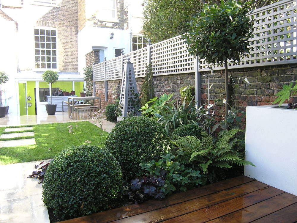  Structural planting divide the hardwood decking area from the stone-edged lawn in this modern North London garden design by Living Gardens. 